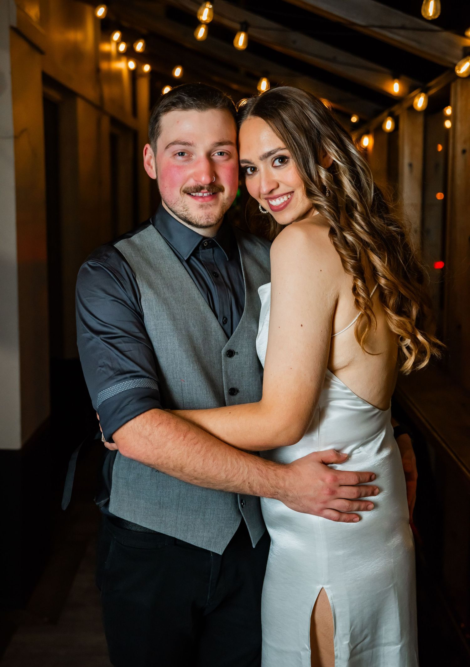 A couple shares an intimate moment in a dimly lit hallway with romantic lighting and warm ambiance.