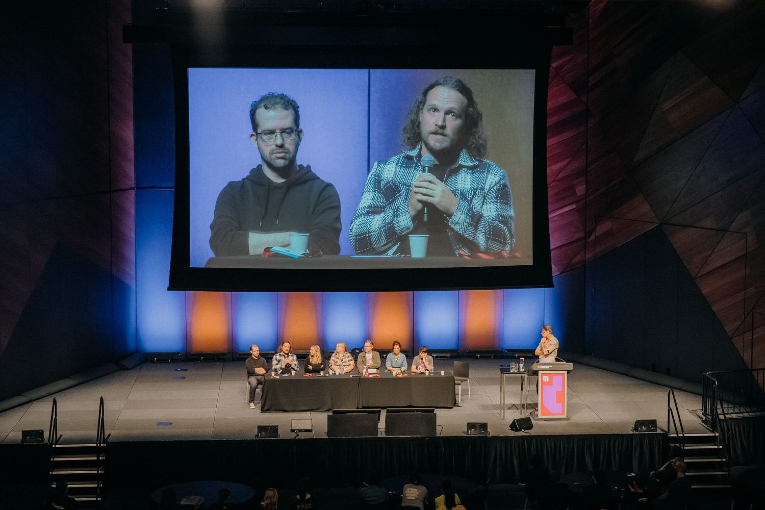 A series of five similar images showing a wide stage setup with large projection screens displaying video content.