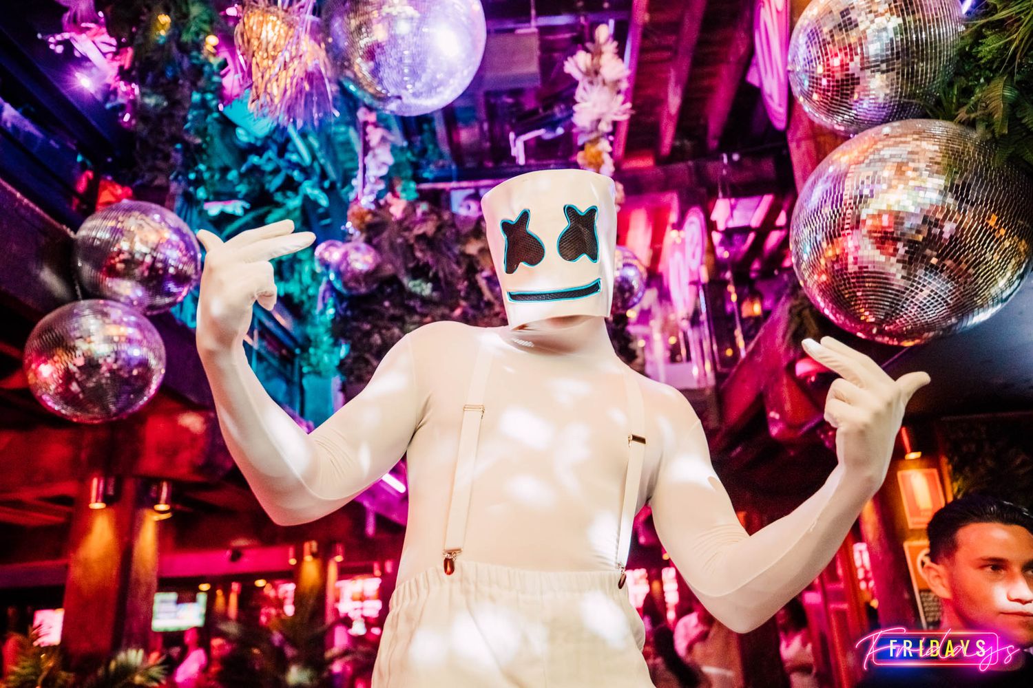A lively nightclub scene with disco balls and vibrant pink and purple lighting illuminating the dance floor.
