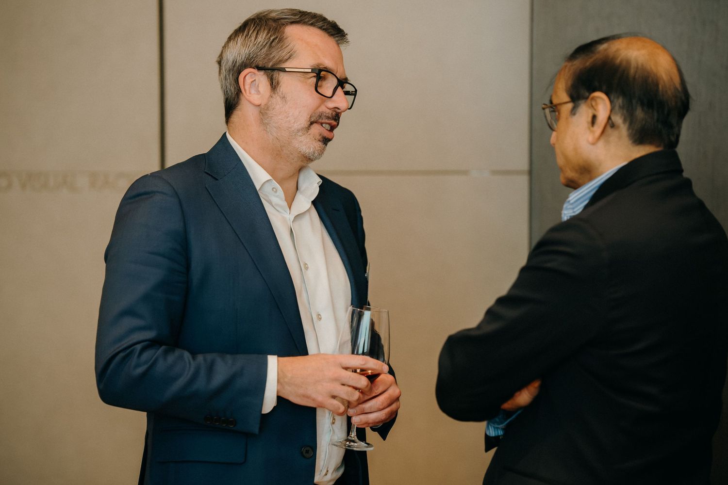 Business professionals in dark suits engage in conversation while networking at a professional event.
