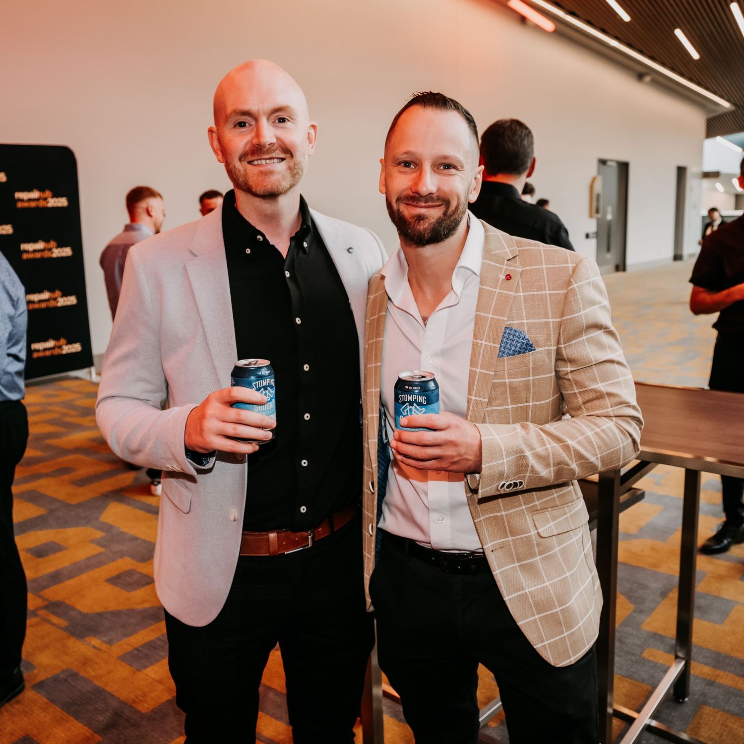 Three people in business attire networking and socializing at a corporate event with drinks.