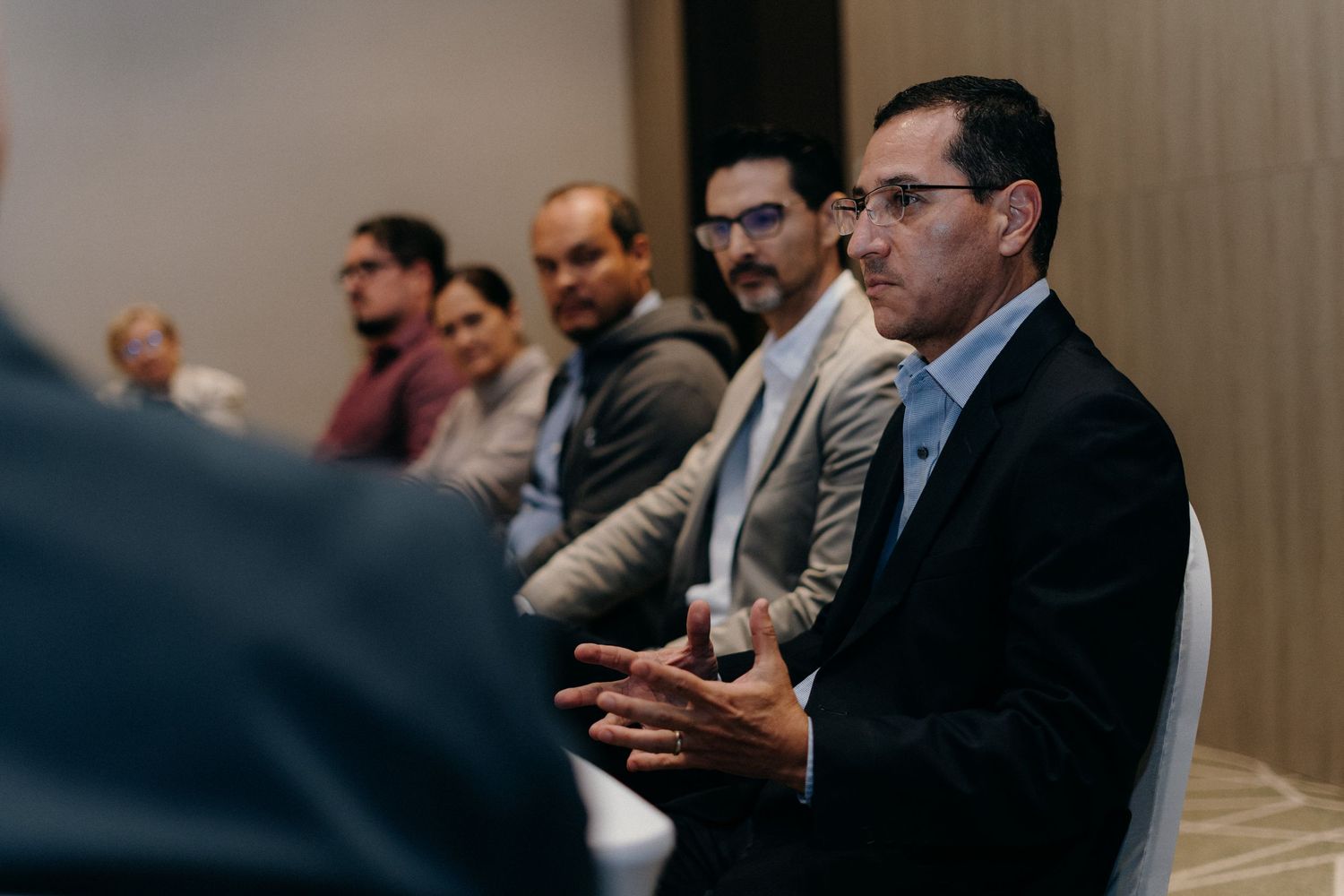 Business professionals sitting at conference table during corporate meeting in modern office setting.