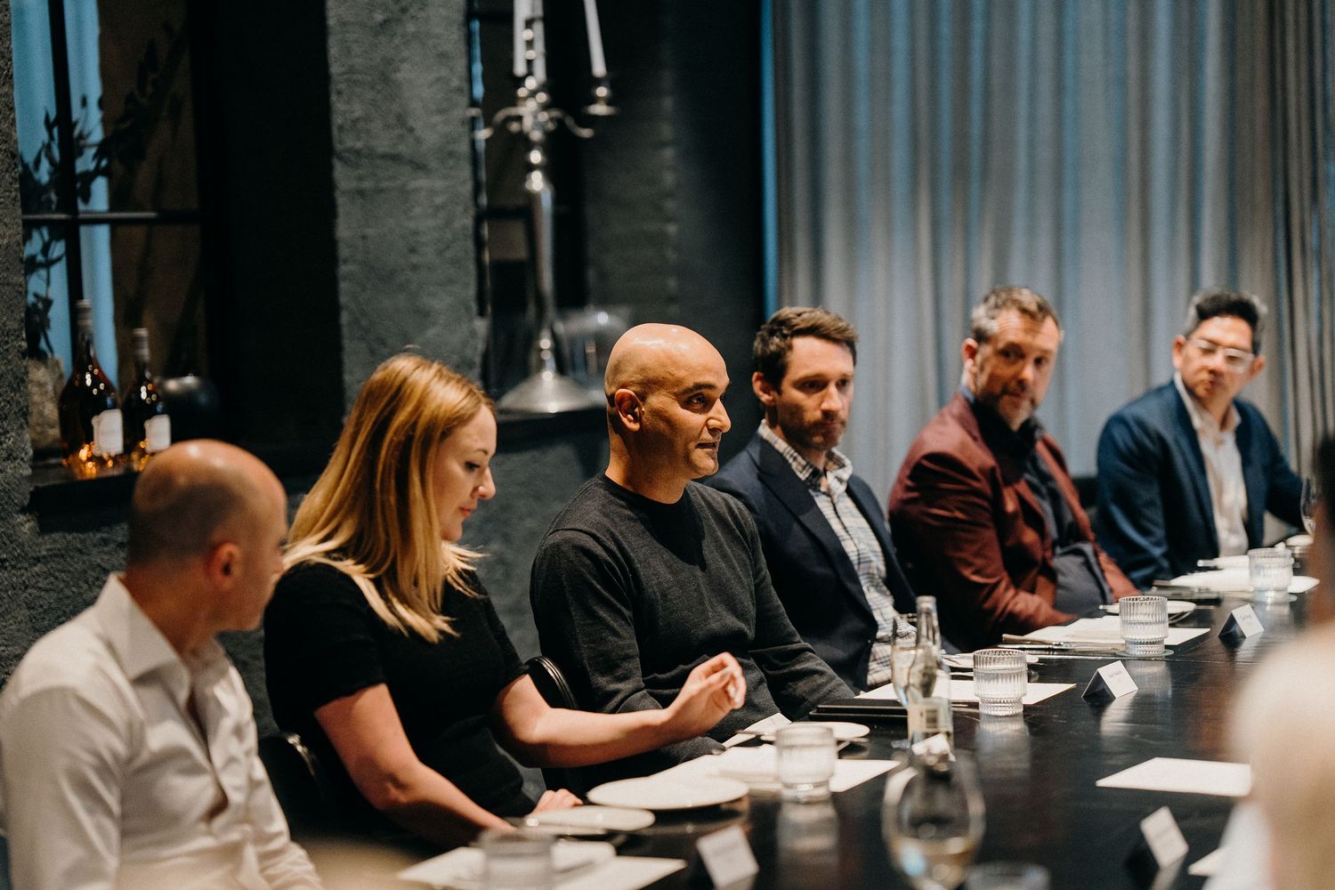 Business professionals seated at a long conference table participate in a collaborative meeting session.