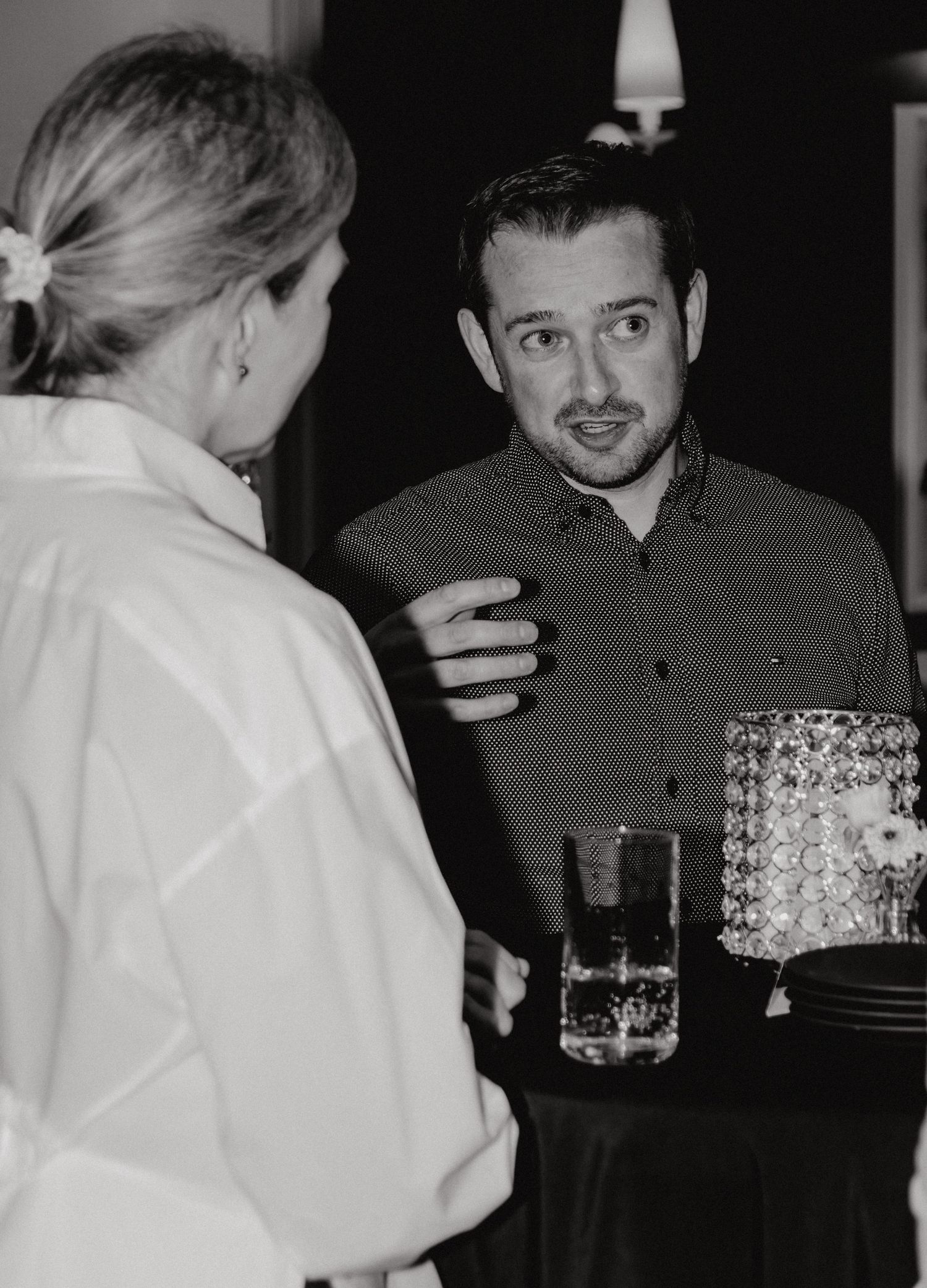 A black and white series of photos showing people interacting at what appears to be a social gathering or event.