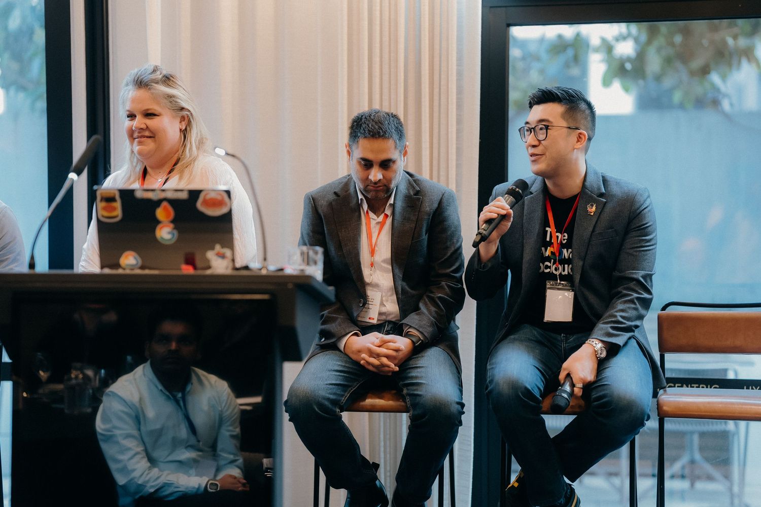 Business professionals in dark attire sit and engage in conversation during a networking event.