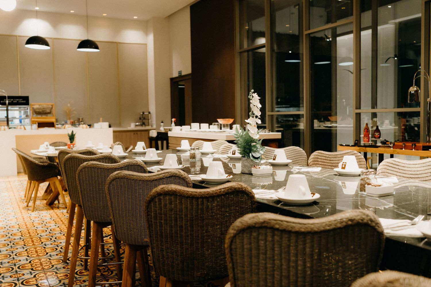 Modern restaurant interior with warm lighting features rattan chairs and elegant table settings in a contemporary dining space.