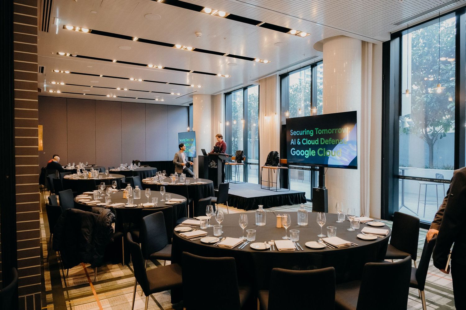 Modern restaurant interior with round tables and chairs set for dining in a bright space with large windows.