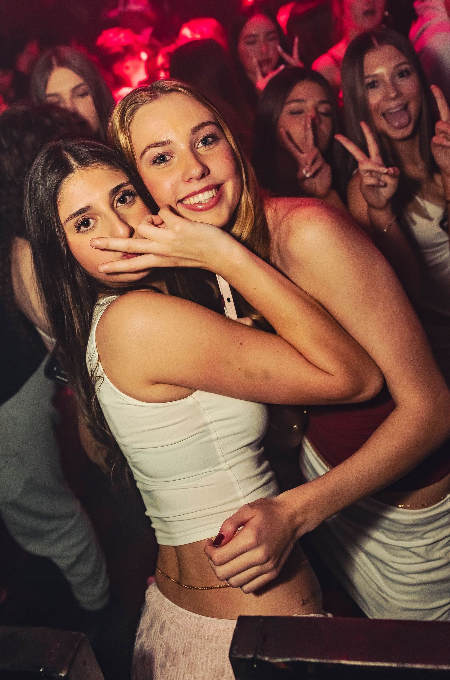 People dancing and having fun in a crowded nightclub with red lighting effects.