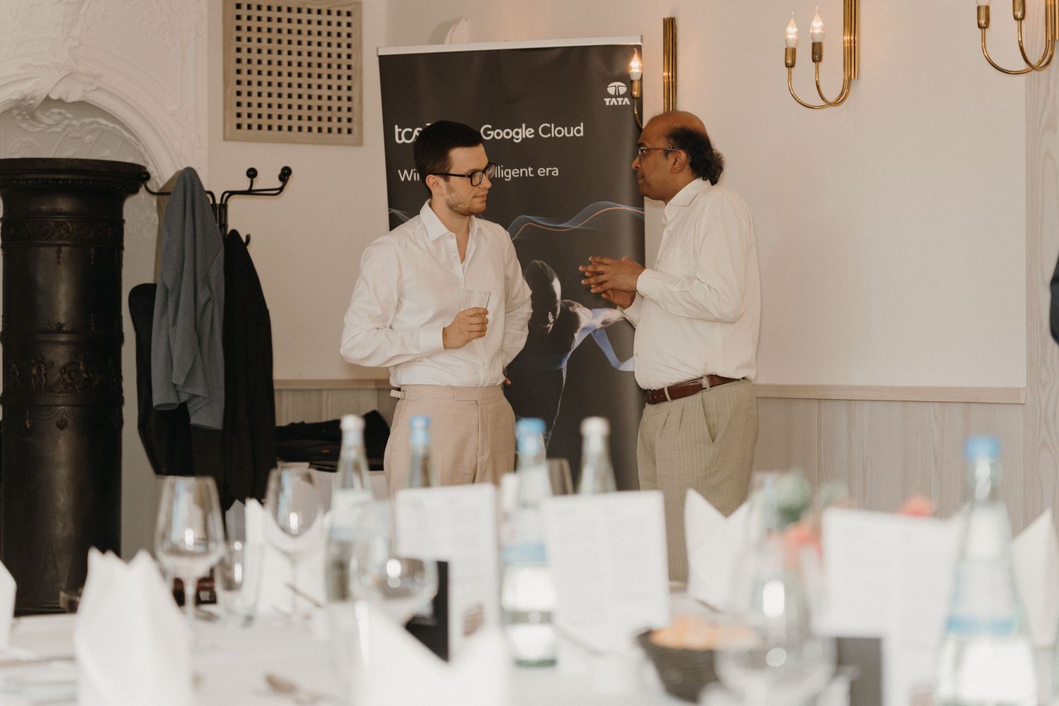 Two professionals networking at a Google Cloud event, standing near branded banner in elegant dining venue.