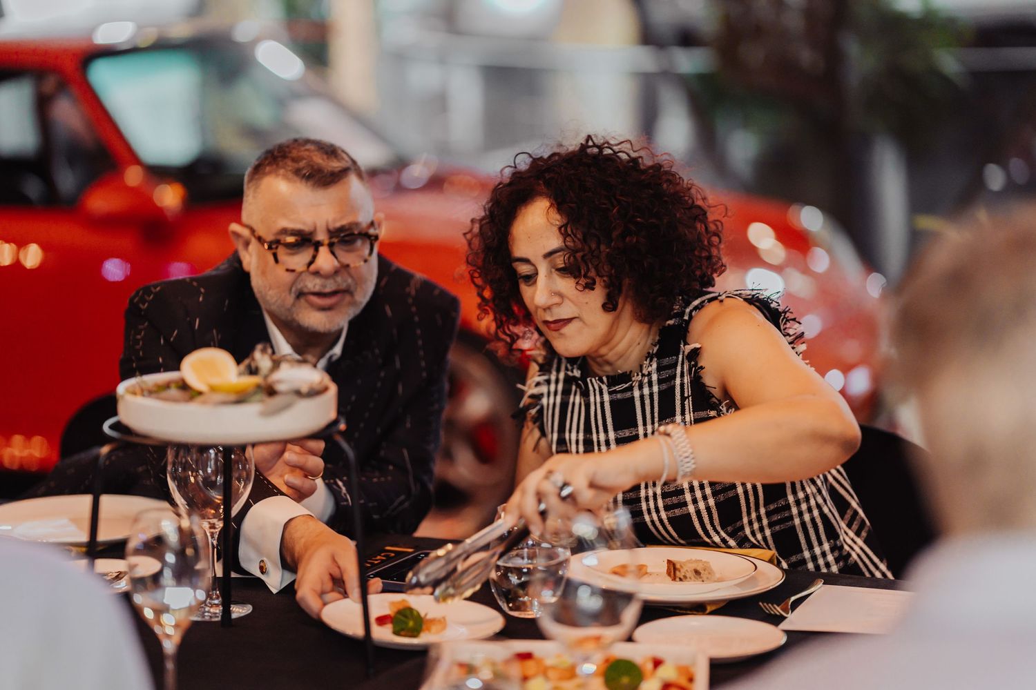 People enjoying a meal together at a restaurant with warm lighting and festive atmosphere.