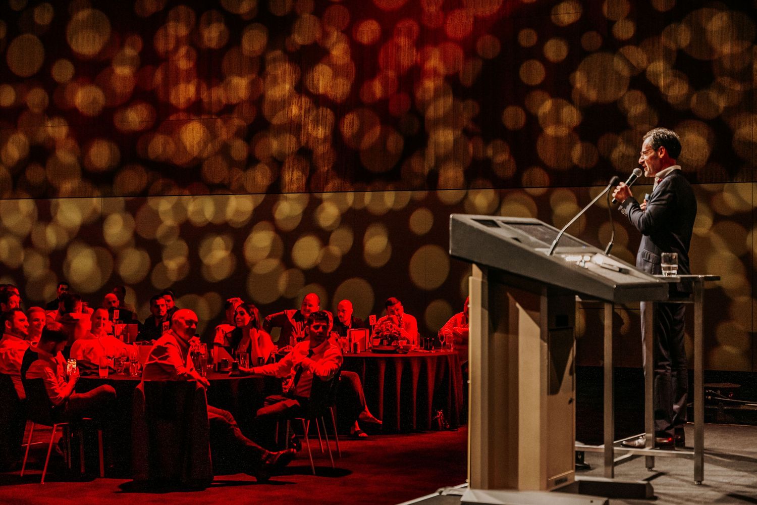 Concert pianist performs on grand piano in front of orchestra during classical music performance on stage.