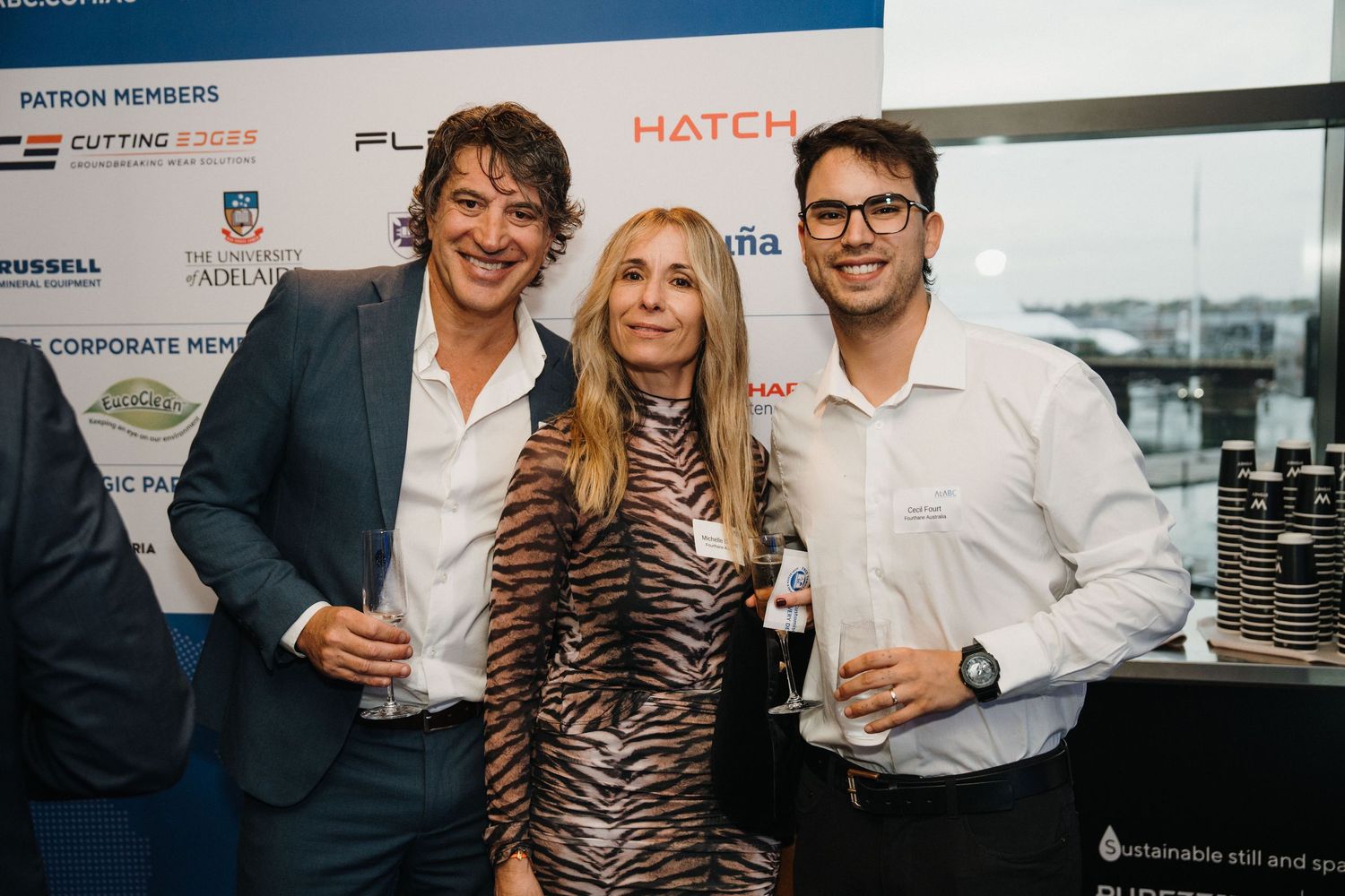 Group of professionals networking at a business event with drinks in hand.