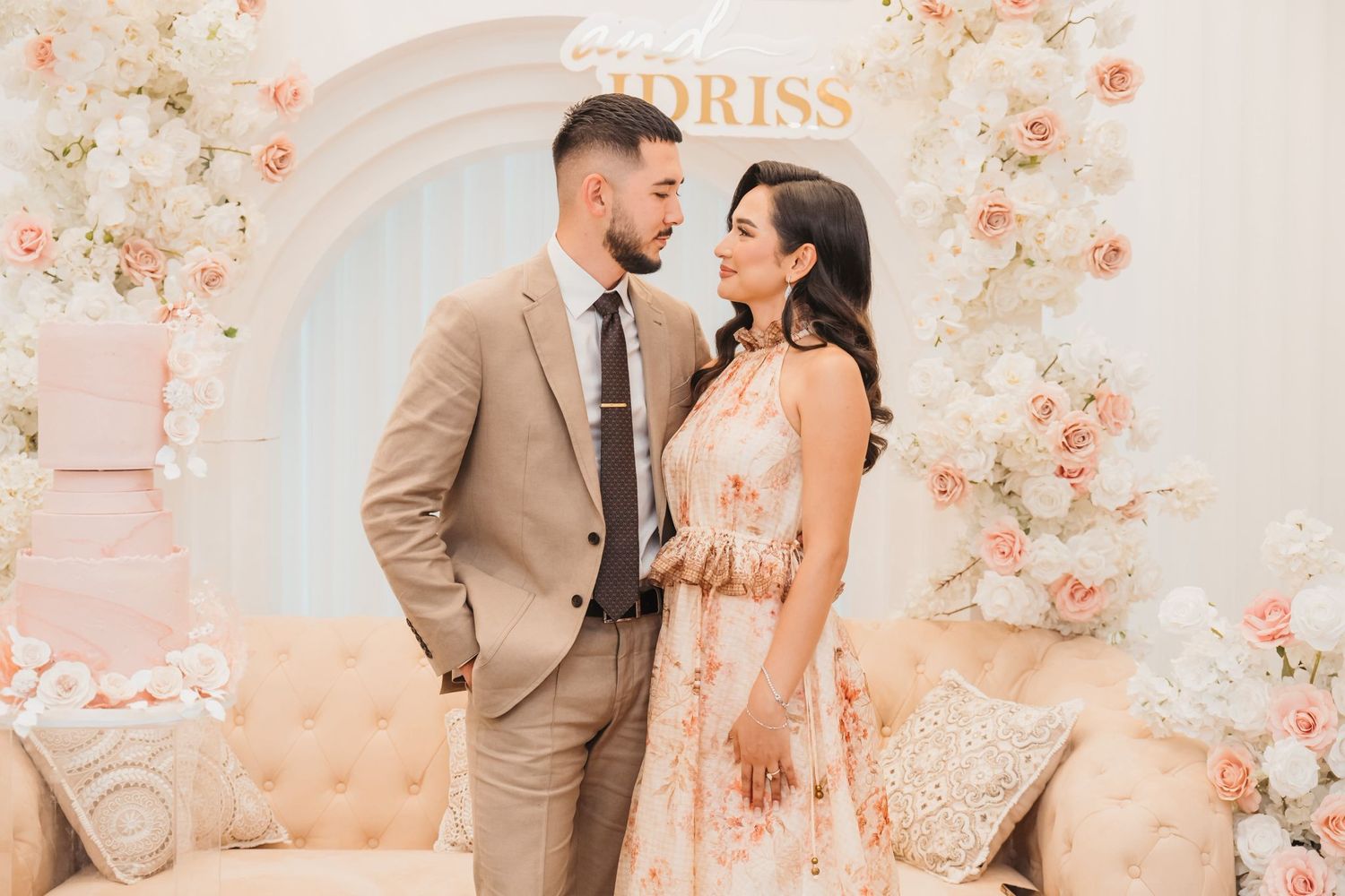 A romantic moment captured in front of a peach and blush floral backdrop at an elegant wedding ceremony.