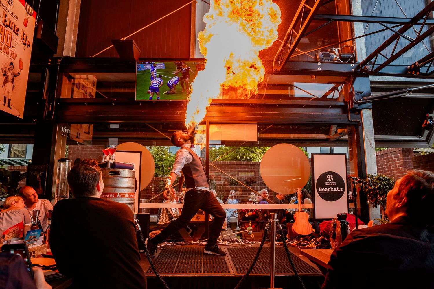 Orange pyrotechnic effects create dramatic lighting at an indoor event space.
