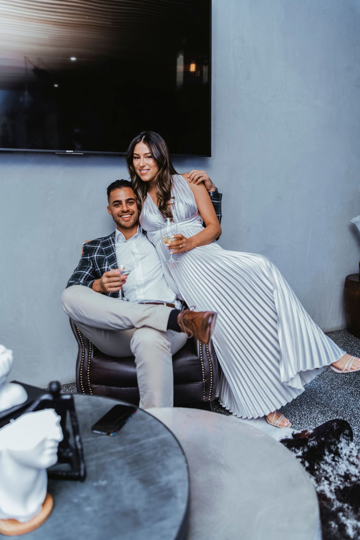 Couple relaxing and laughing together on a gray couch in a modern living room.