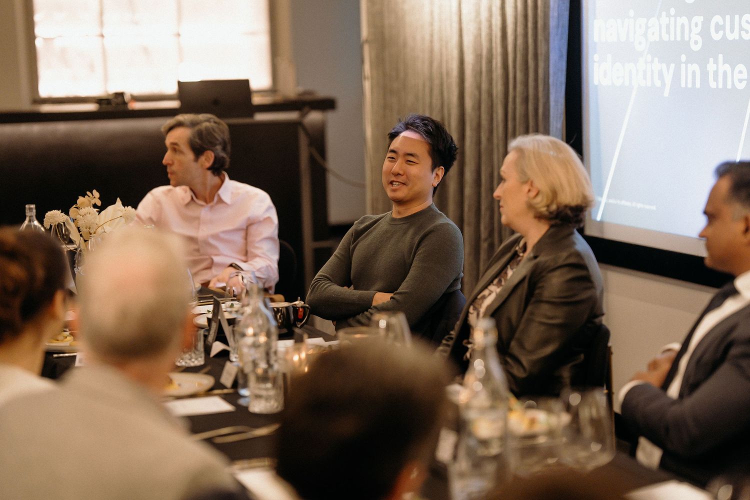 Business professionals seated around conference tables engage in discussion during a corporate meeting.