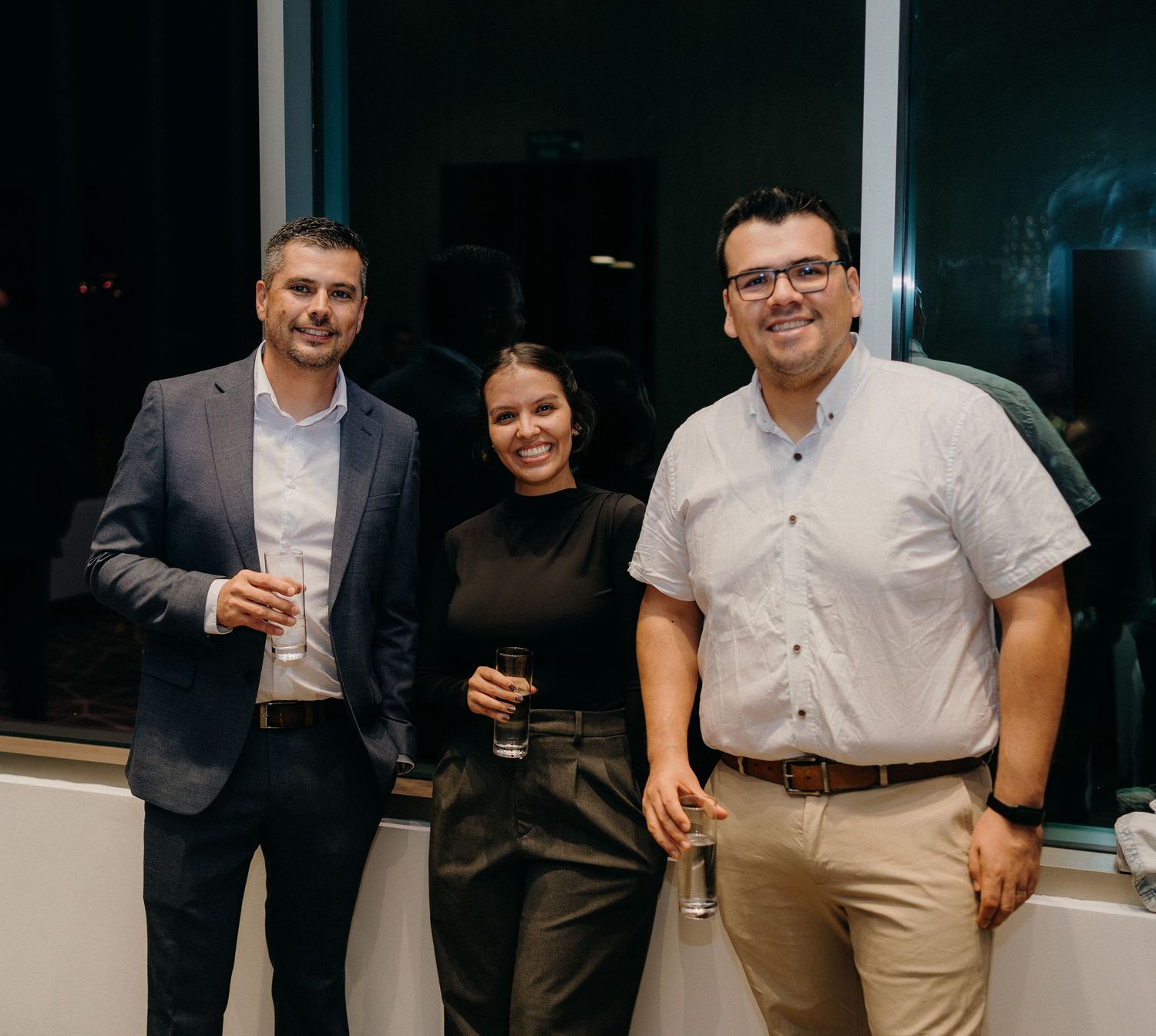 A group of people in business casual attire standing together and socializing at an indoor event.