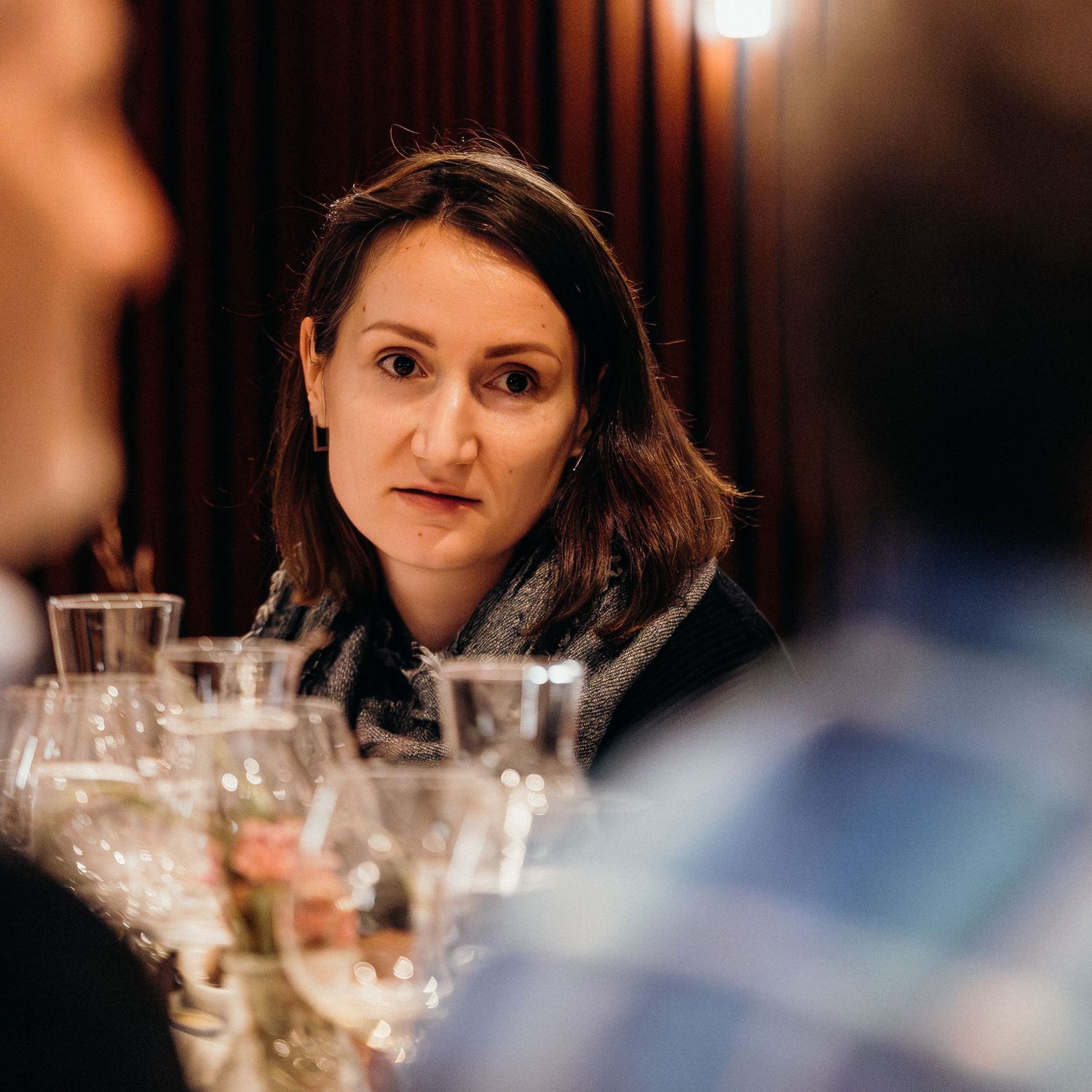 A sequence of wine glasses and table settings at an elegant dinner party, with soft lighting creating an intimate atmosphere.