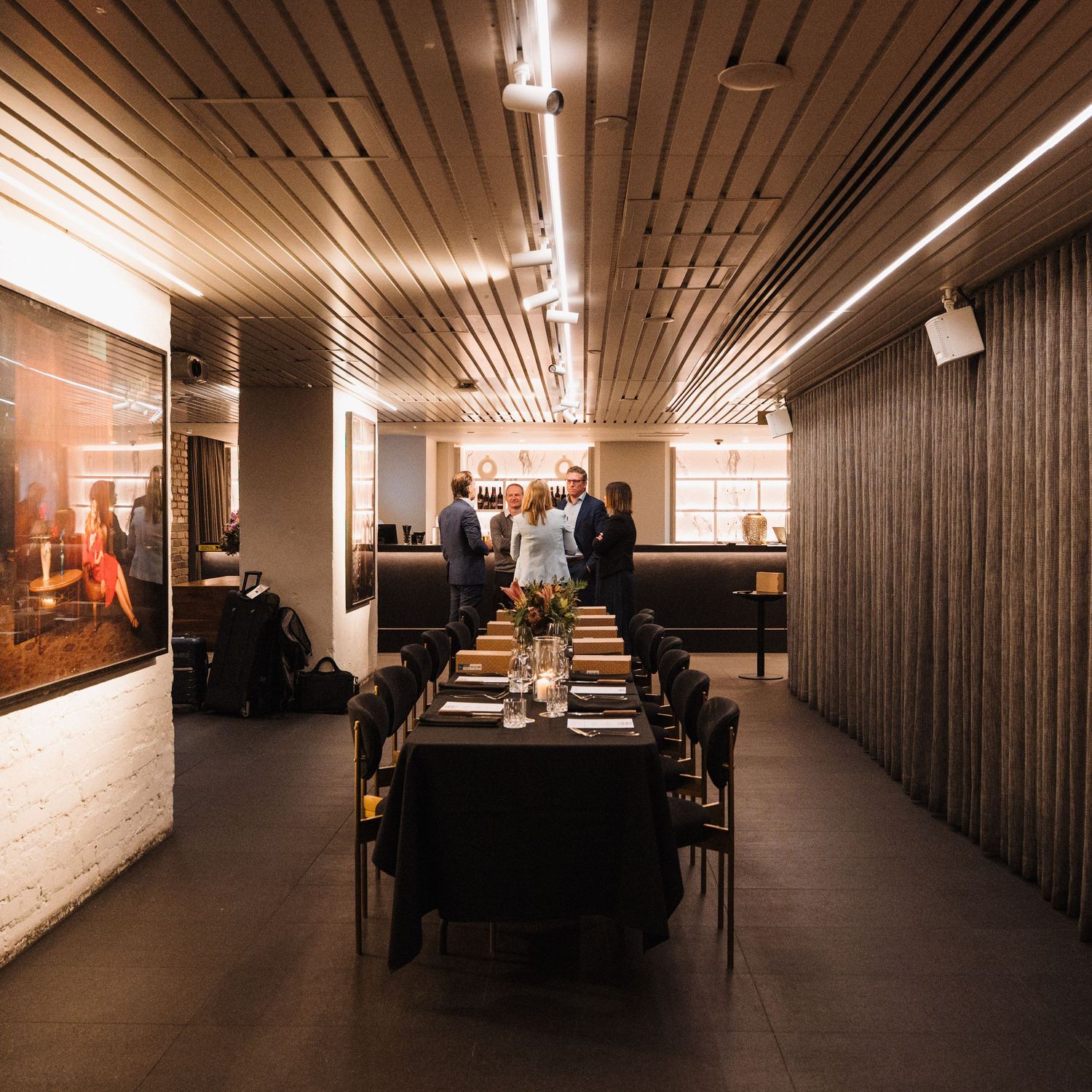 Long hallway in a modern office building with wooden panels and overhead lighting creating a warm ambiance.