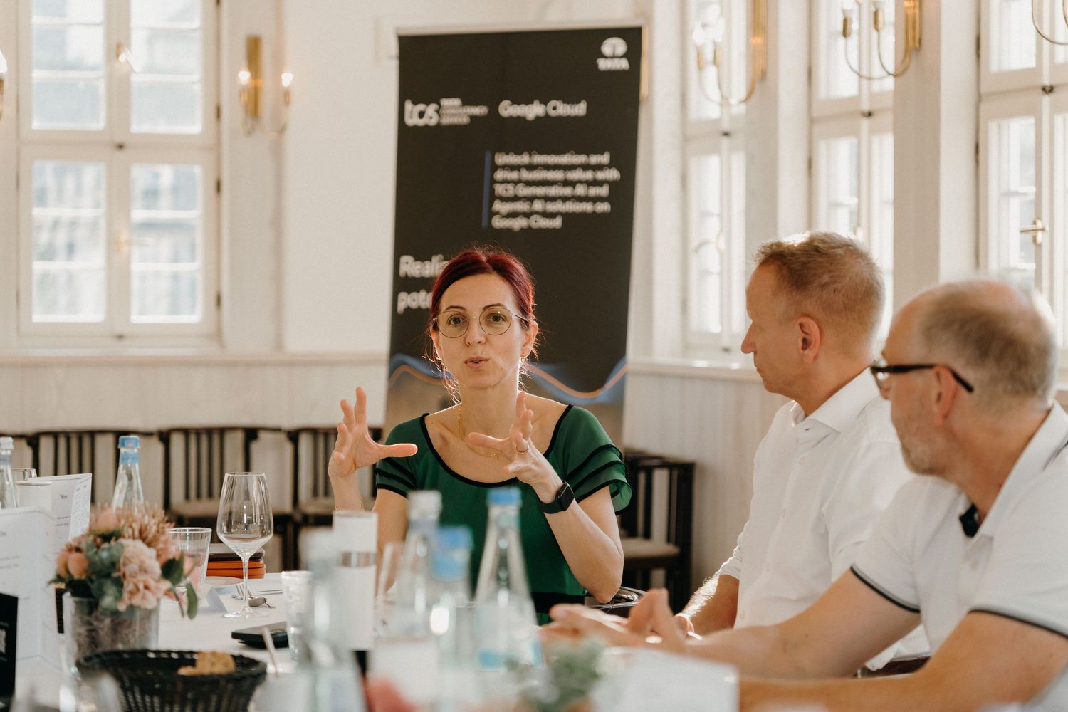 Business professionals engaged in discussion at a Google Cloud innovation roundtable event in a bright conference room.