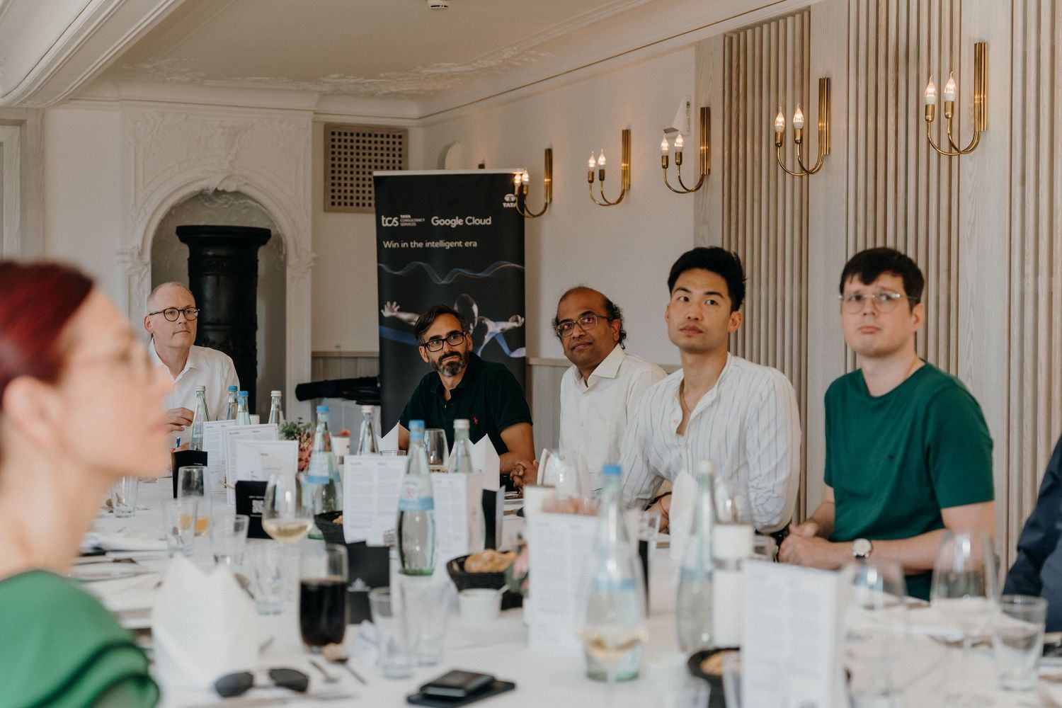 Business professionals attend a Google Cloud conference panel discussion at an elegant dining table setting.