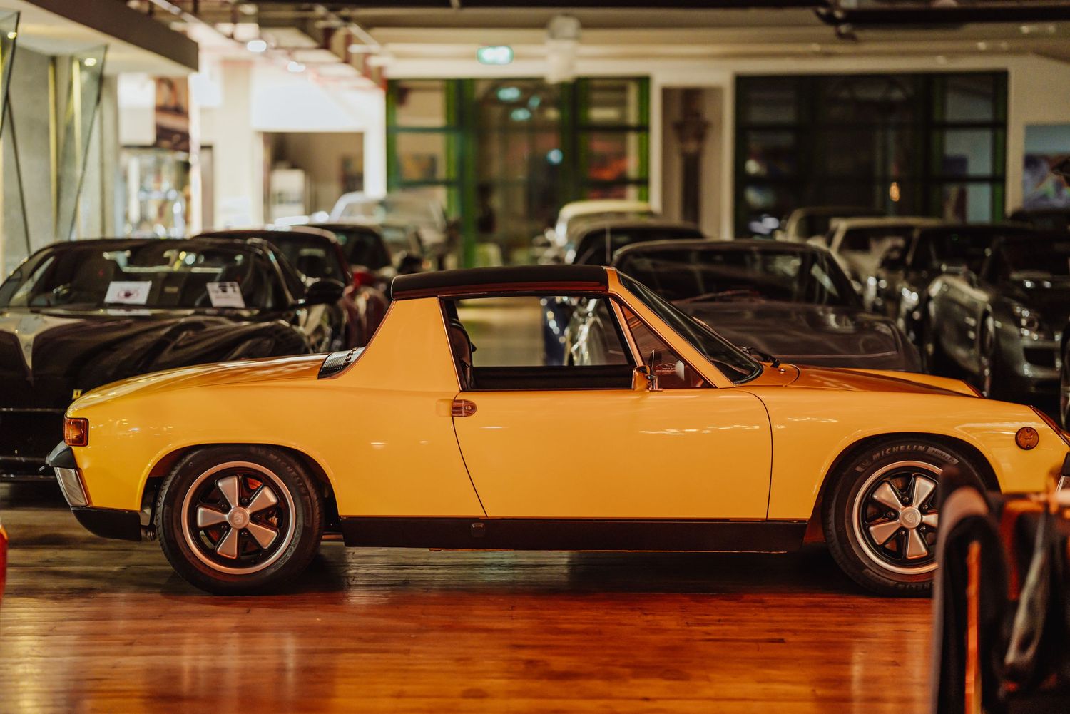 A row of classic vintage sports cars on display in a showroom featuring sleek designs and polished finishes.