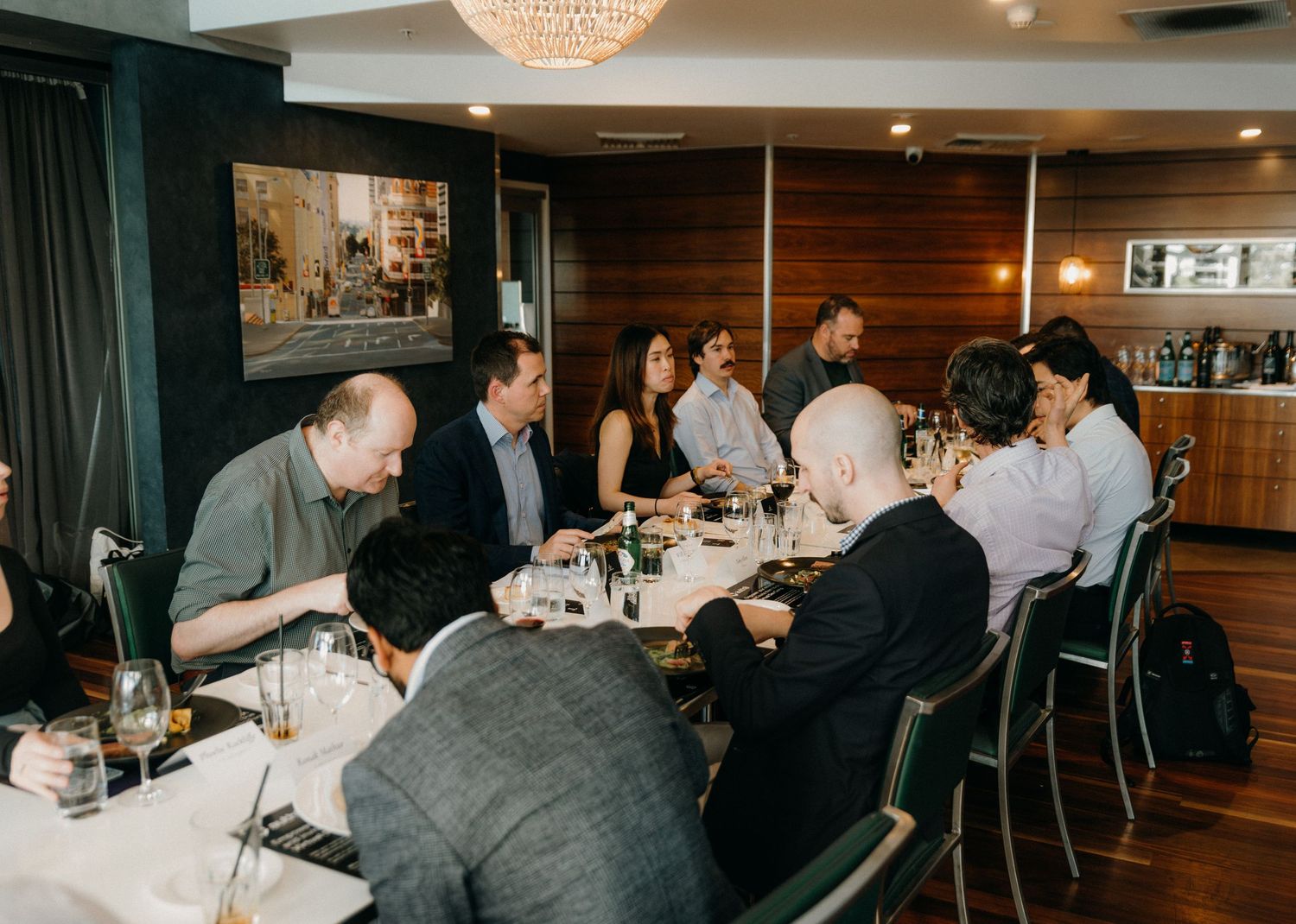Restaurant guests seated at a bar counter enjoy drinks and conversation in a warmly lit dining establishment.