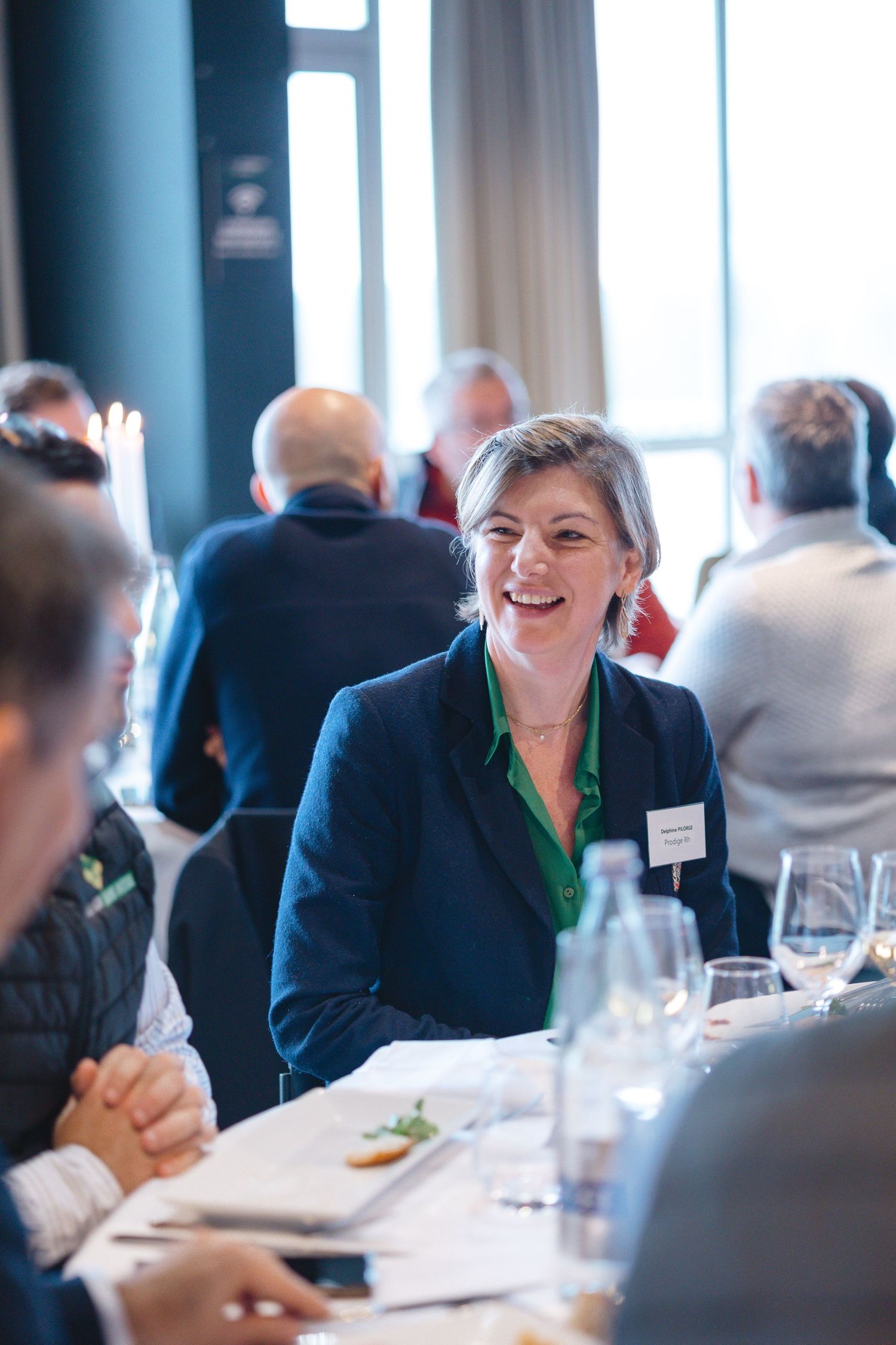 Business networking event with attendees gathered around dining tables for discussion.