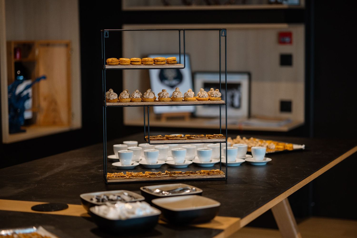 Tiered display of pastries and desserts on modern black shelving.