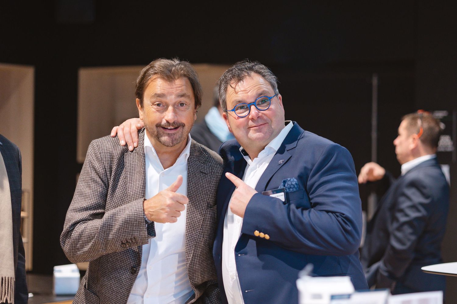 Two attendees share a friendly moment at a formal business conference.