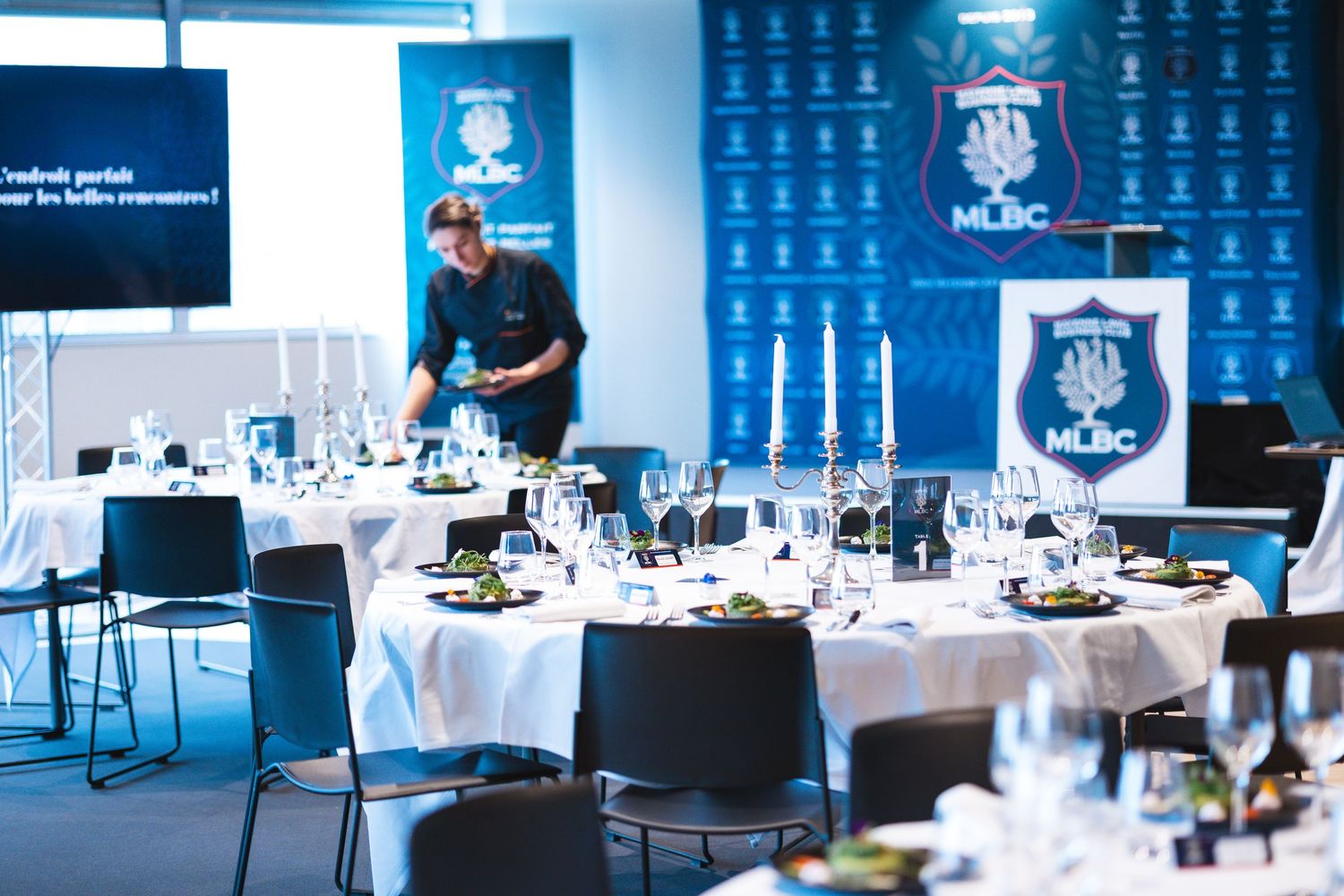 Elegant banquet hall setup with blue lighting and formal table settings.