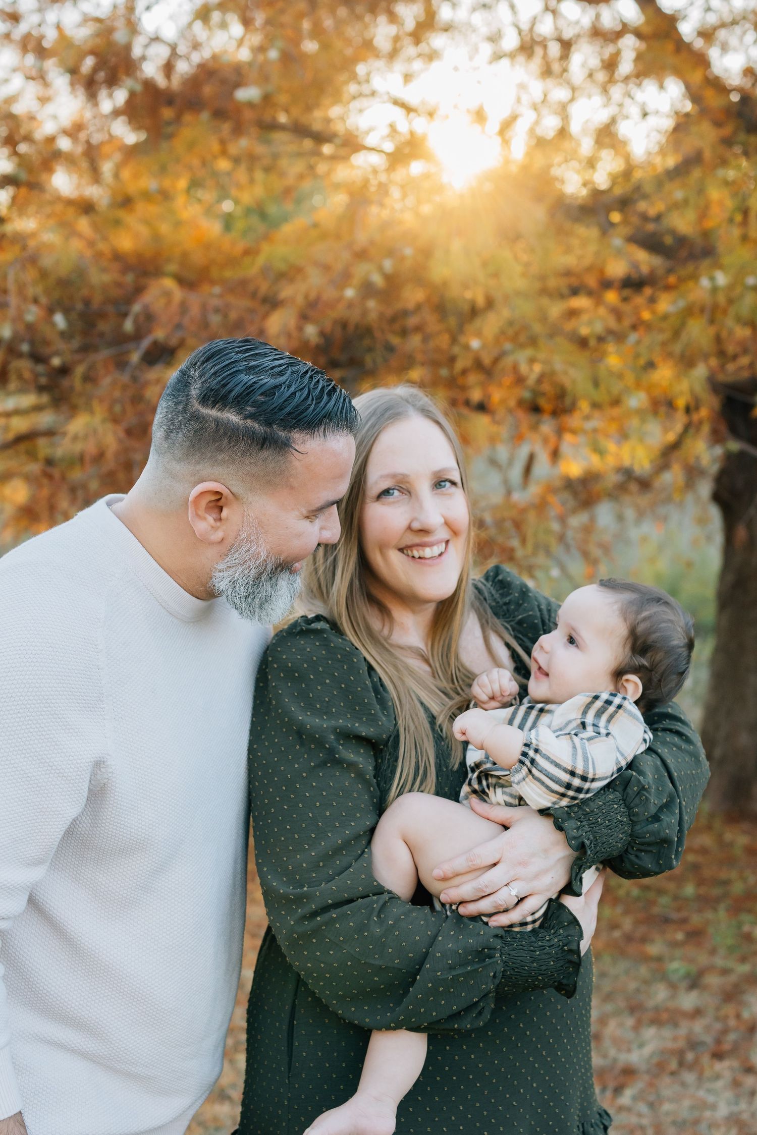 Family sharing intimate moment together during sunset in fall foliage.