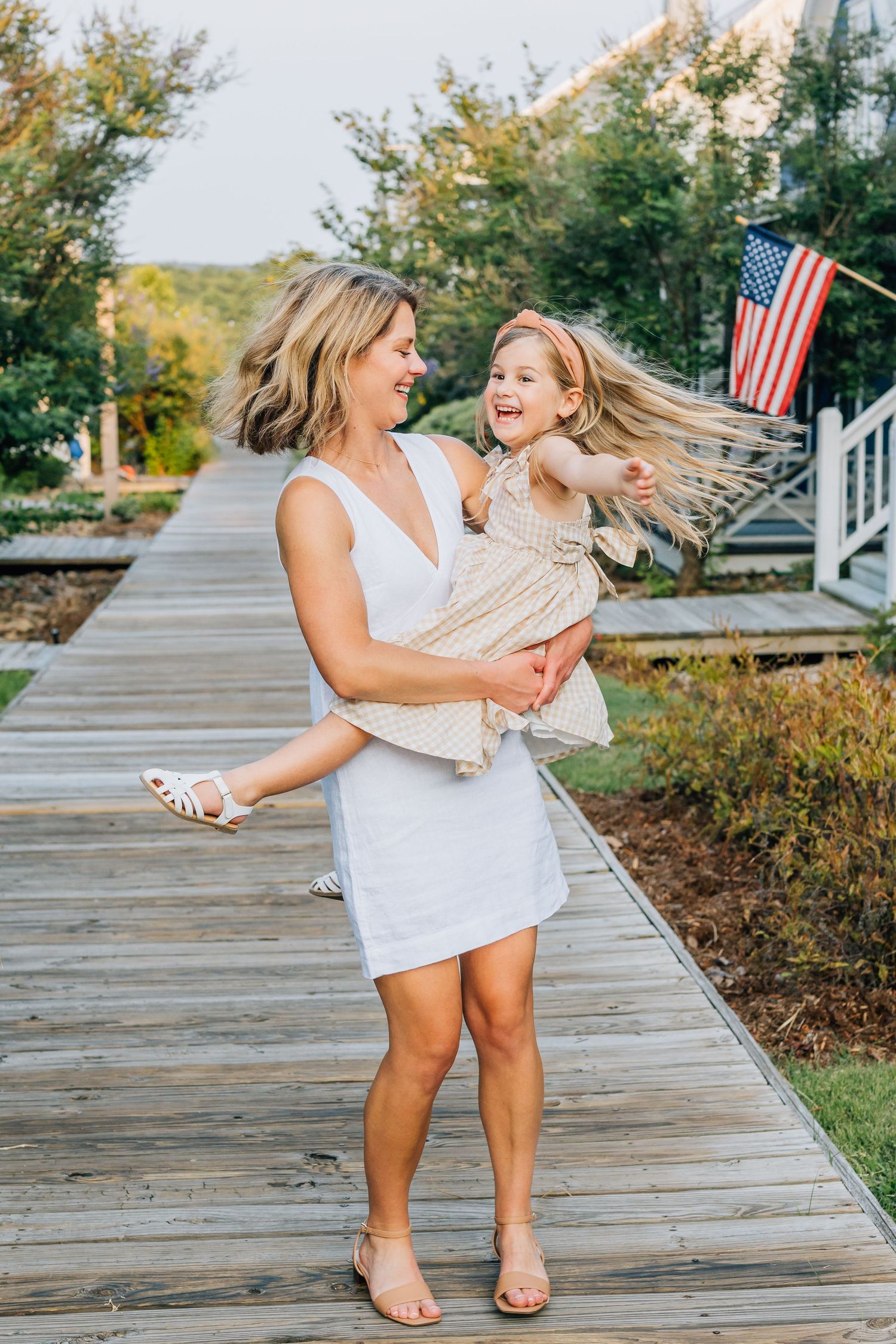 A joyful moment captured on a boardwalk with an American flag in the background.