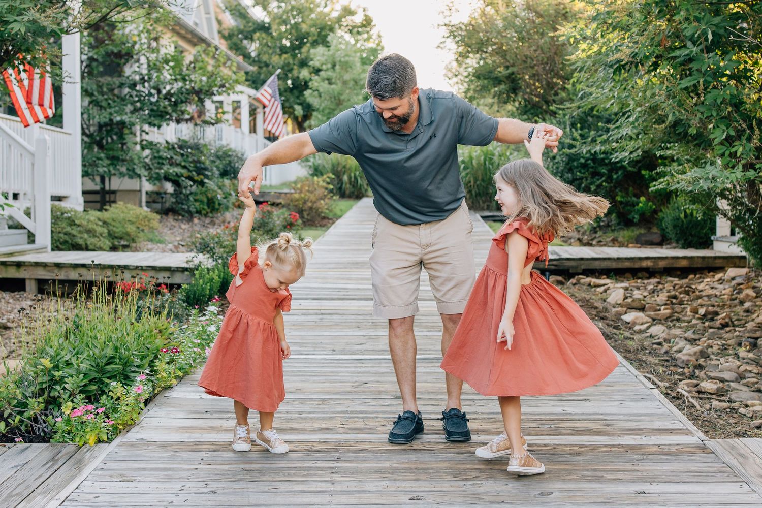 A playful moment on a wooden boardwalk with coral-colored dresses adding a pop of color.