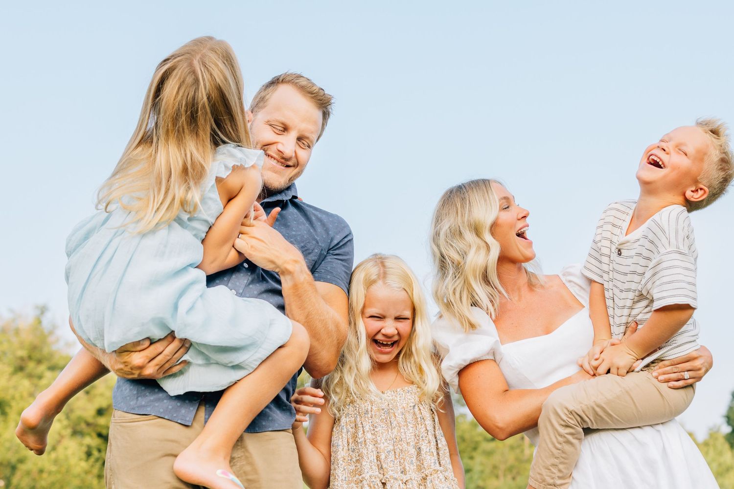 Family enjoying playful outdoor moment together on sunny day.