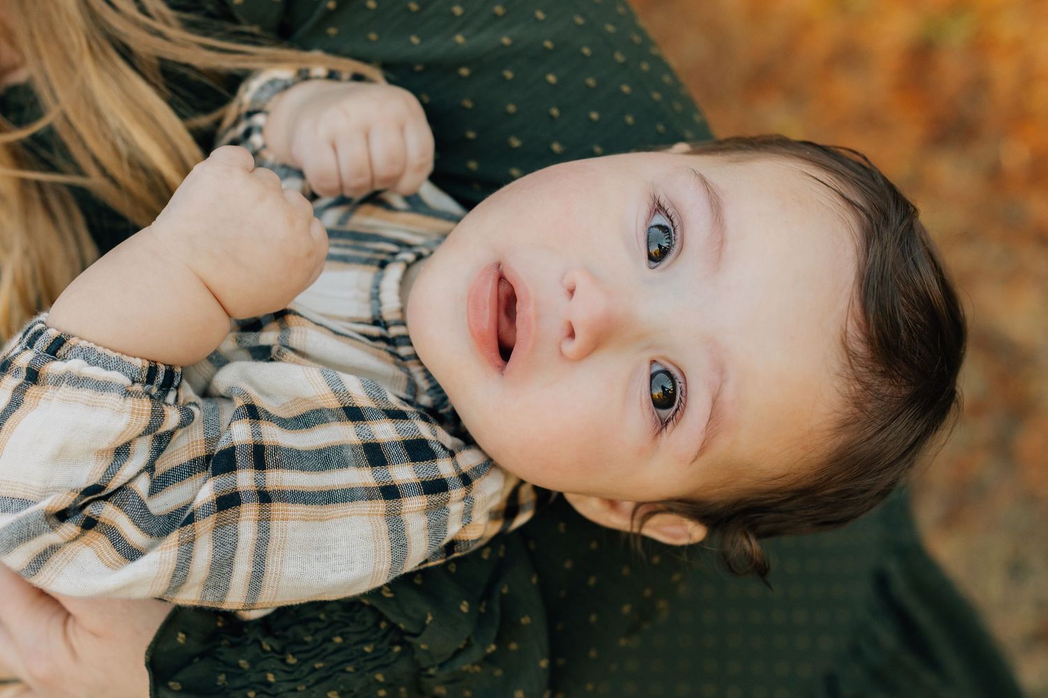 Close up of baby in plaid shirt lying down during fall photo session.