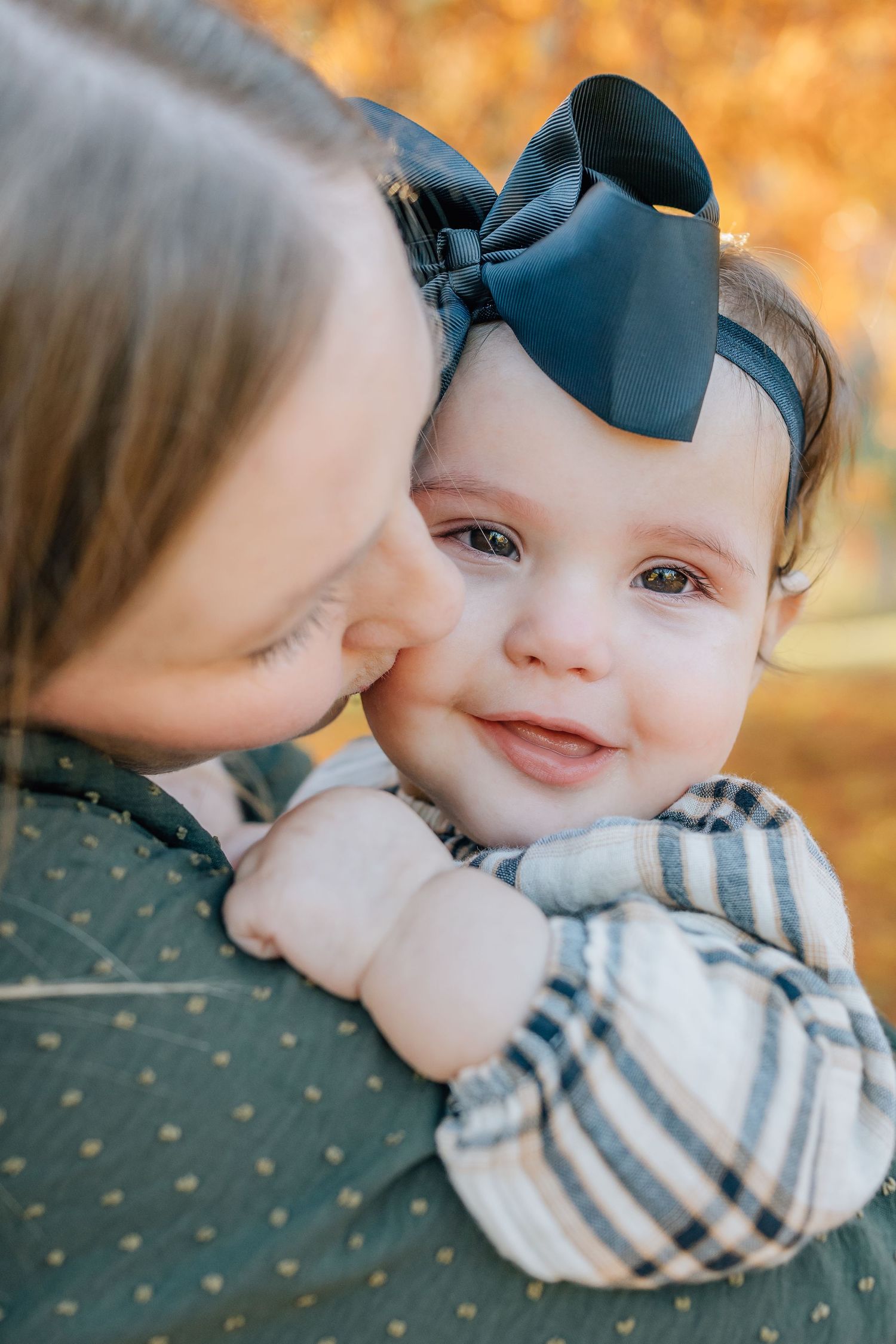 Close-up tender moment with baby wearing blue bow headband.