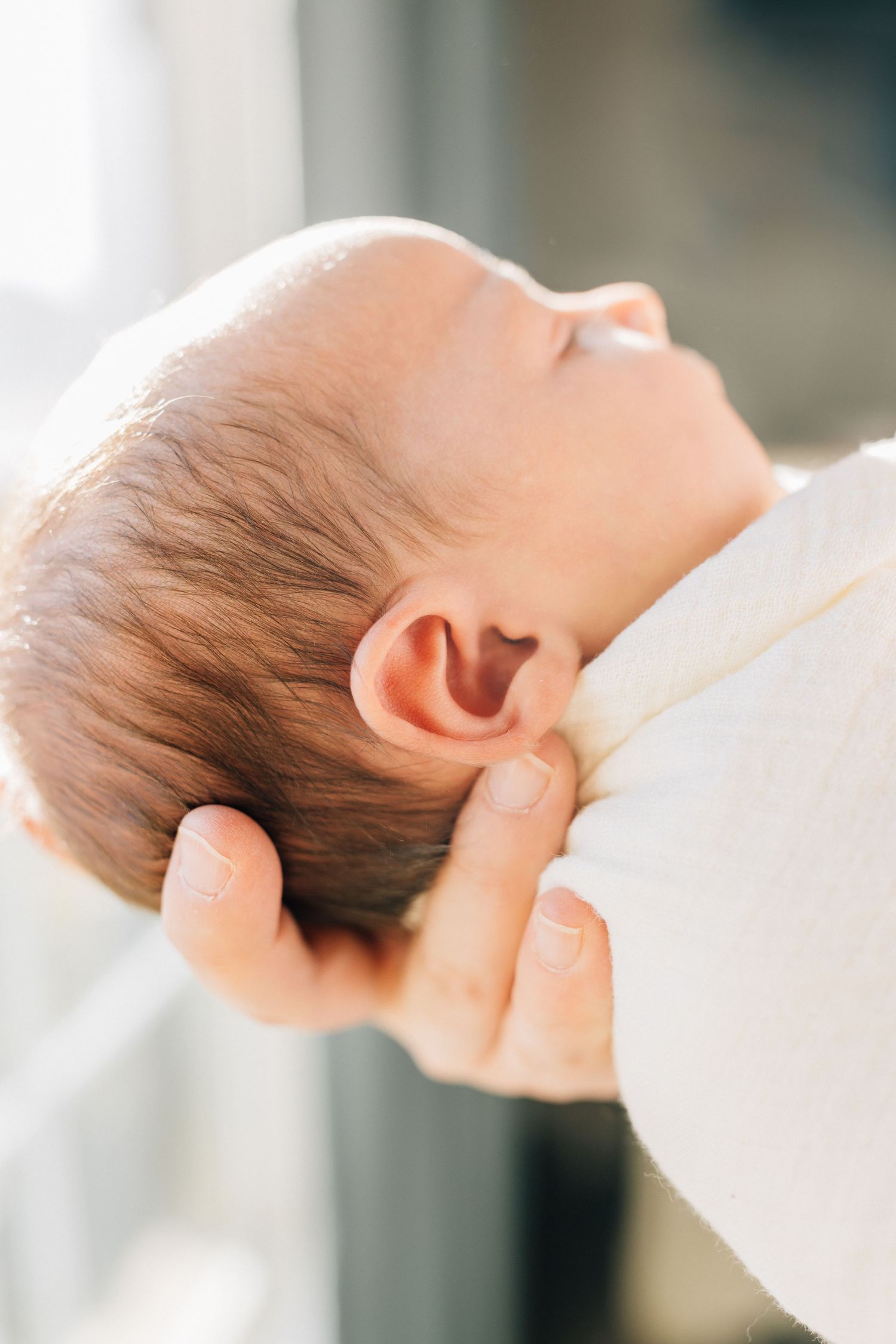 Close-up side view of sleeping infant with soft natural lighting.