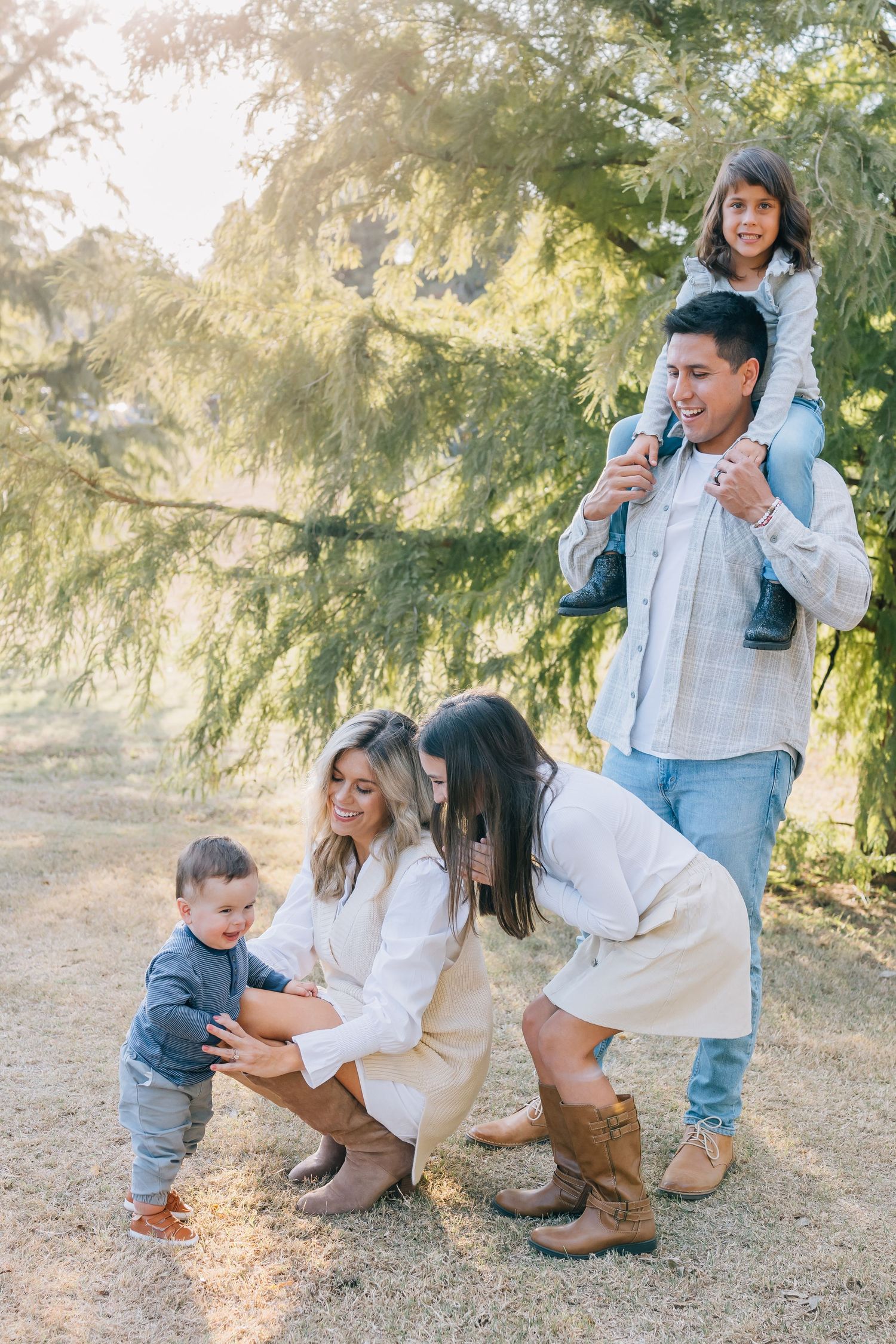 Joyful family gathering outdoors surrounded by evergreen trees on sunny day.