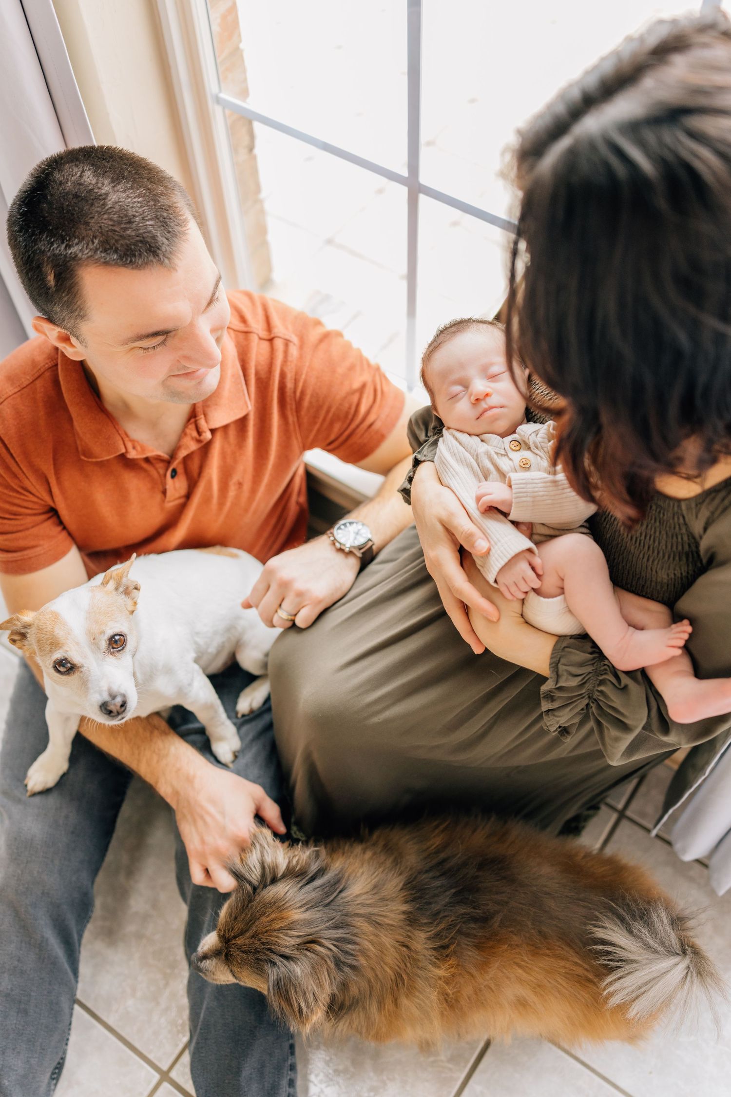Family with newborn baby relaxing at home with two pets.