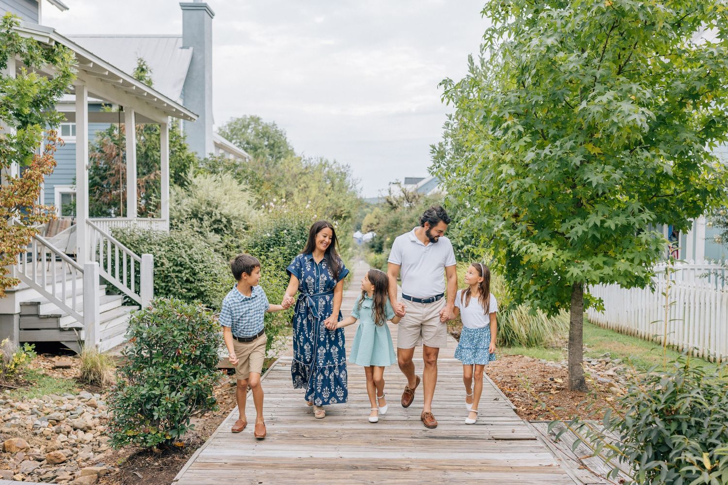 A panoramic collage of family walking on a white picket fence lined path during a sunny outdoor photo session.