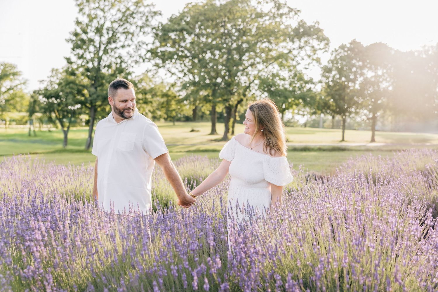 Happy couple enjoying a romantic photoshoot in a blooming lavender field during golden hour.