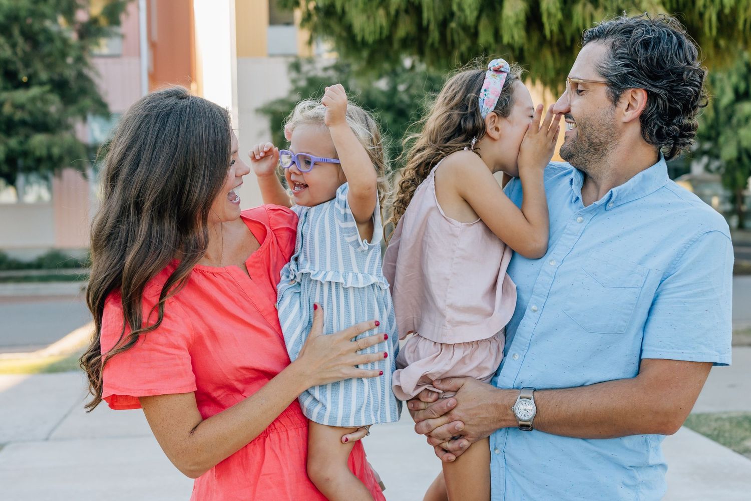 A family in colorful summer outfits share an affectionate moment together outdoors.