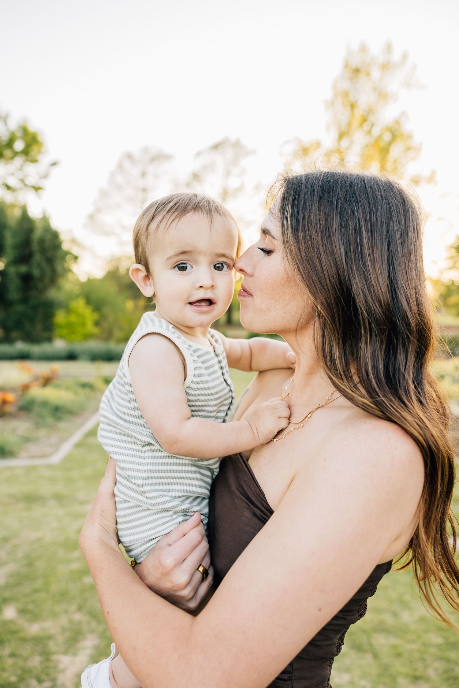A tender moment shared between parent and child outdoors during golden hour in a garden setting.