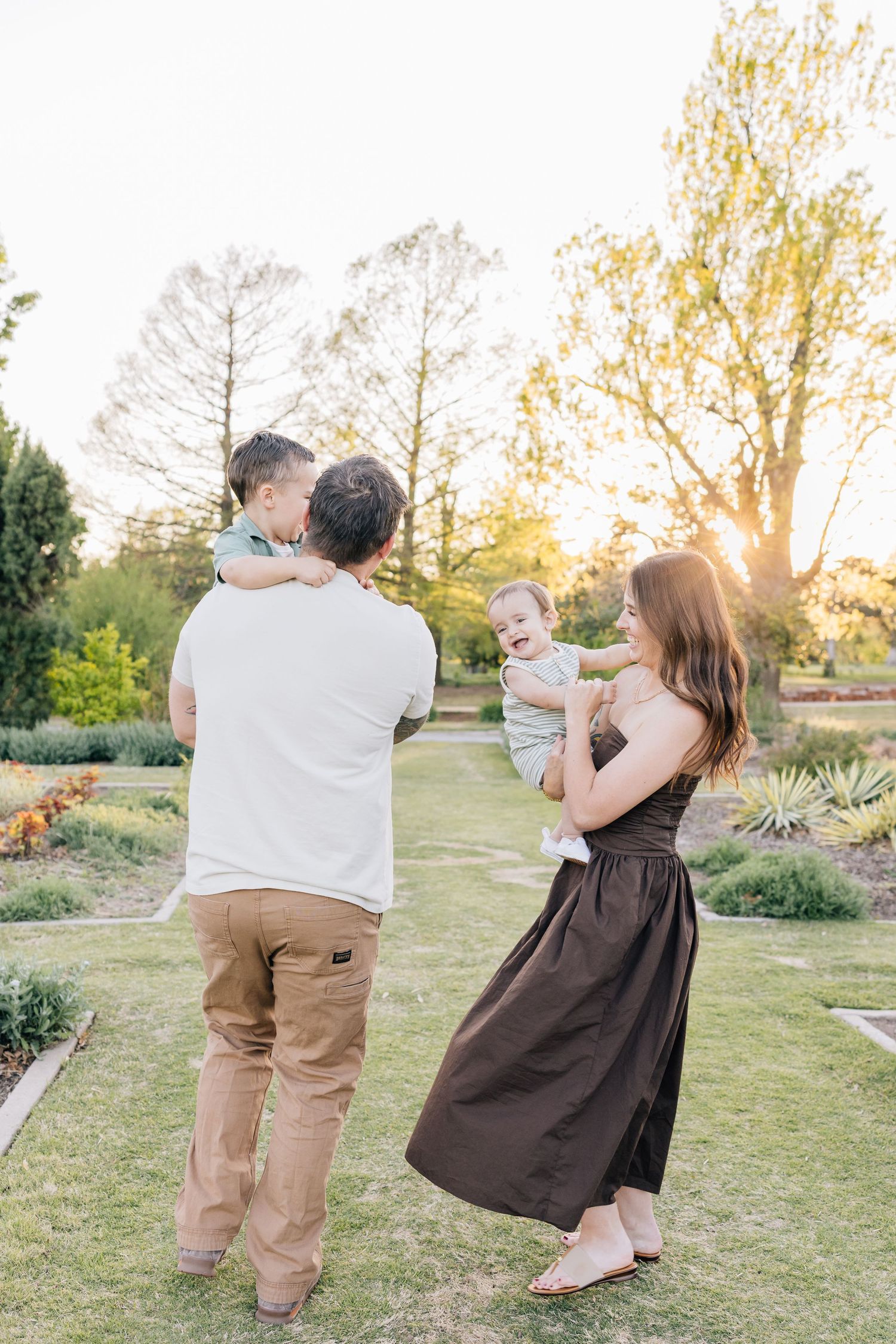 Family enjoying an outdoor moment together in a garden setting during golden hour sunset.