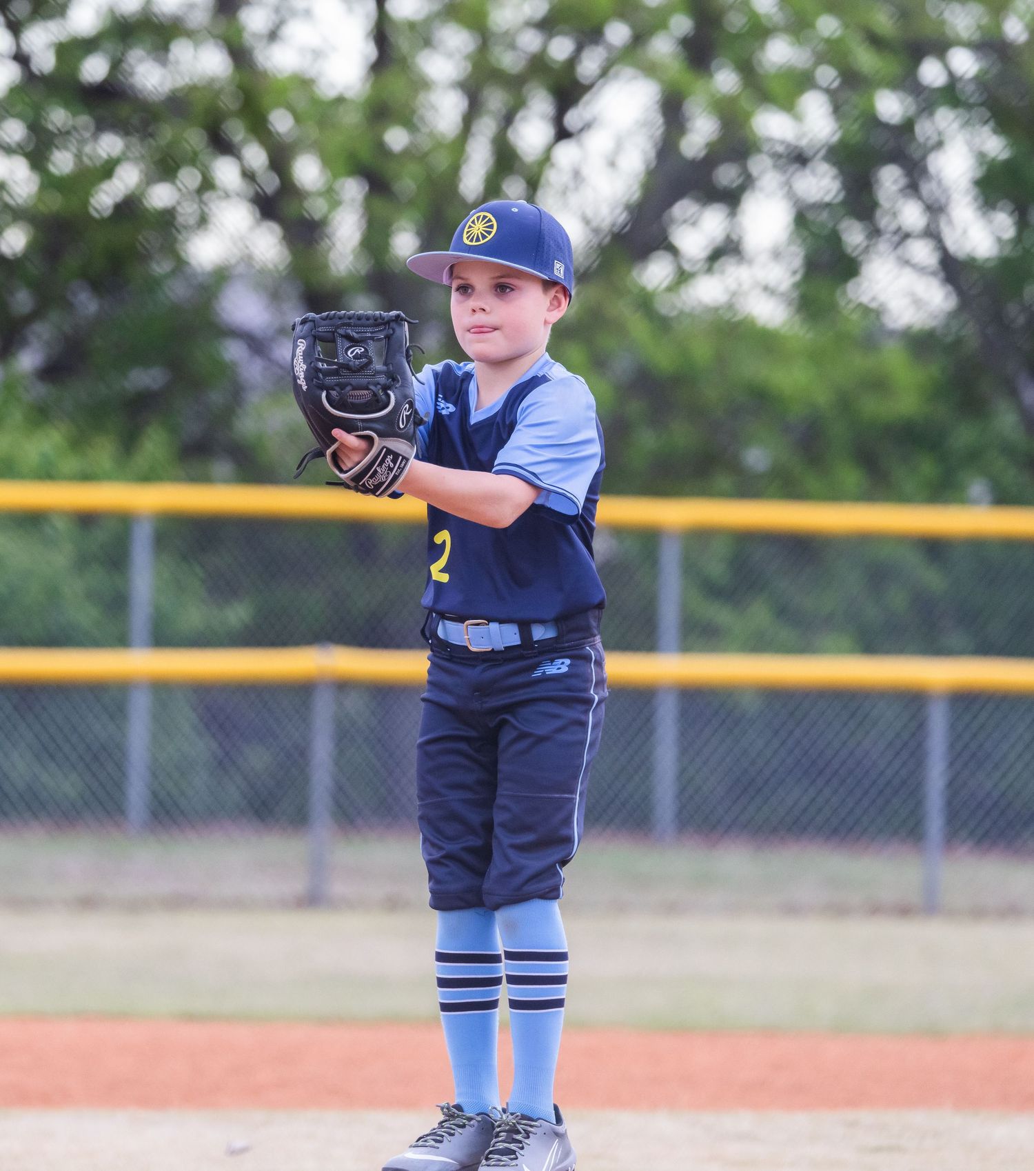 Young baseball player in a blue uniform takes pitching stance on the mound during a game.