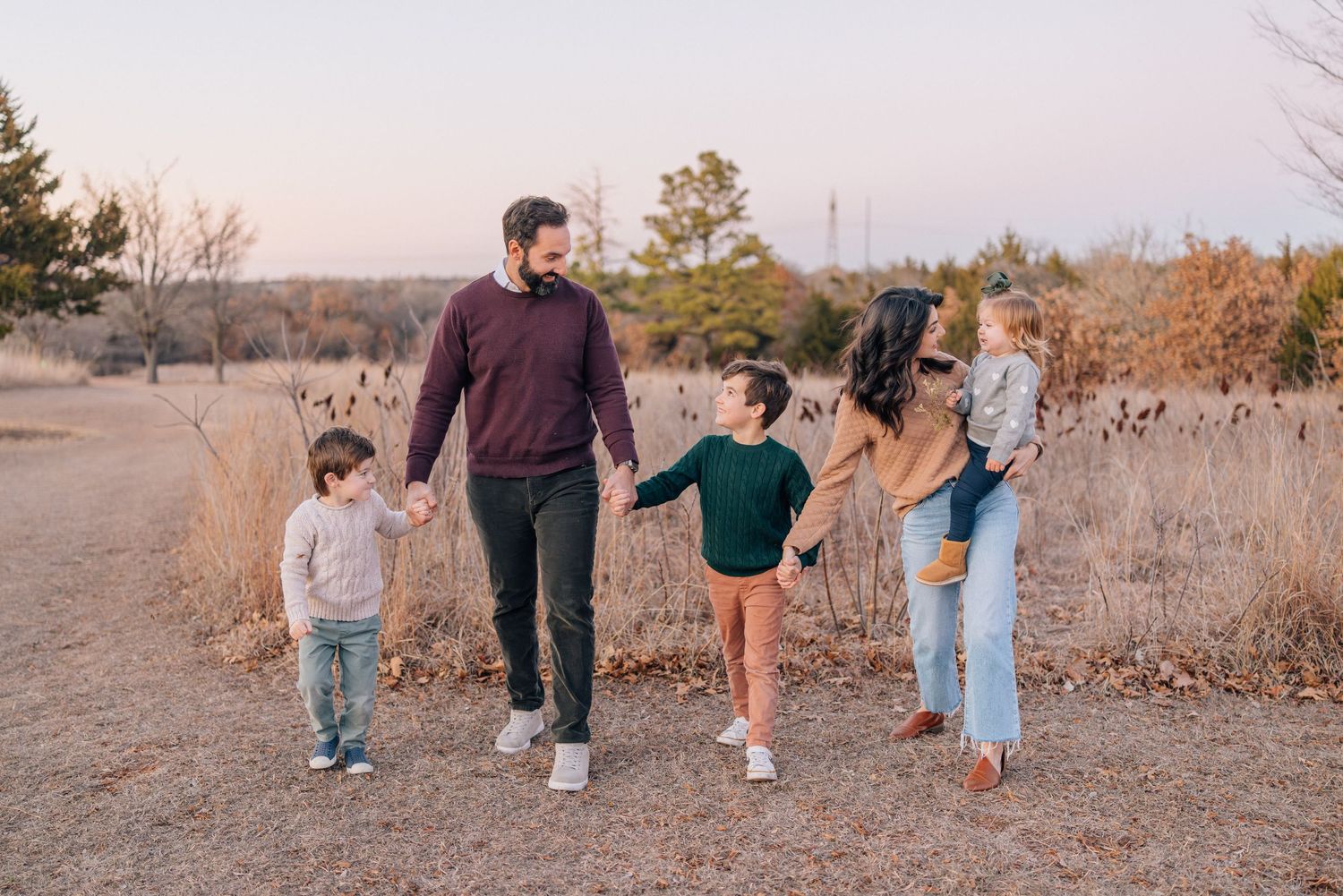 Group walking together on a dirt path during golden hour in autumn scenery.