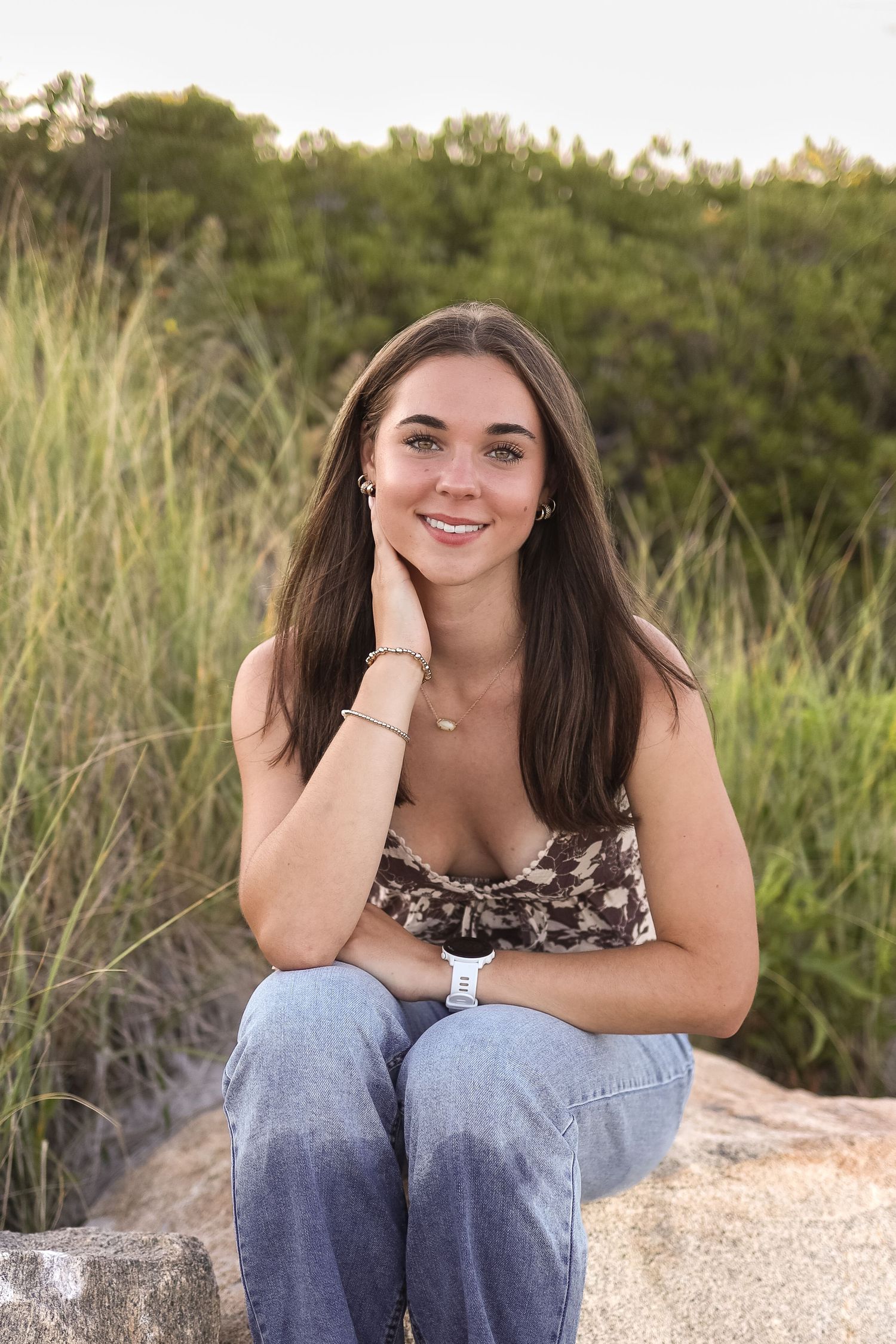 Outdoor portrait session among coastal greenery and sand dunes in casual summer attire.