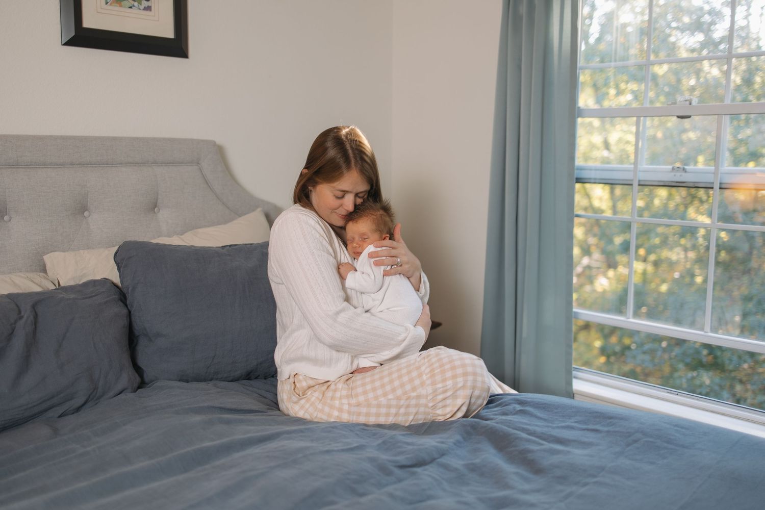 Bright bedroom interior with blue curtains and comfortable bedding by large windows.