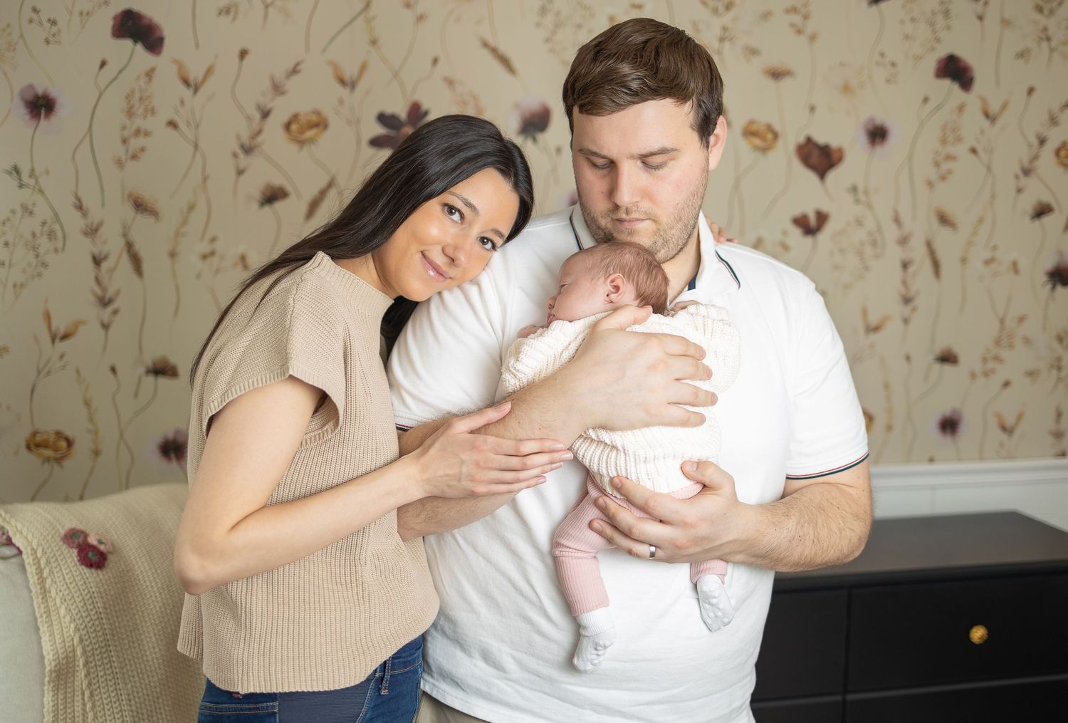 A tender moment of parents holding their newborn baby in a cozy interior setting.